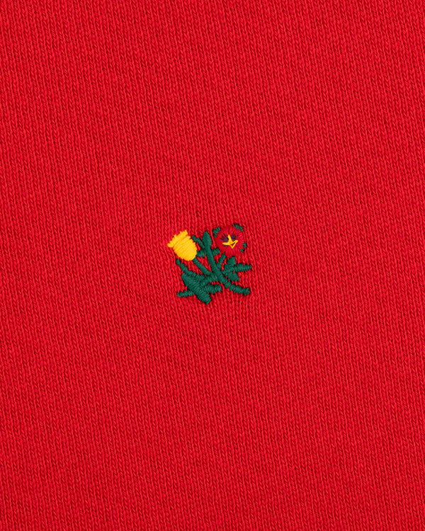 Crest Crewneck Sweatshirt in red fabric with a small embroidered yellow and green thistle design.