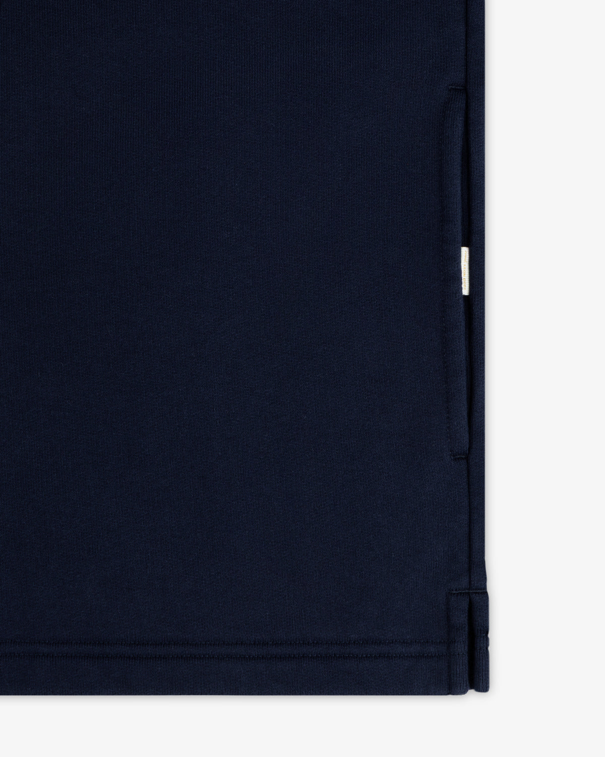 Close-up of the Aimé Souvenir Quarter Zip in navy blue, showing a seam, pocket opening, and small white side tag.