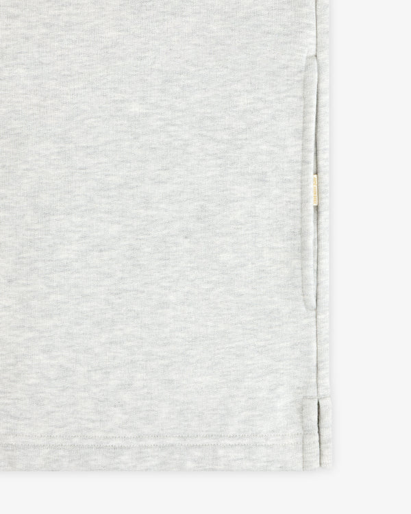 Aimé Souvenir Quarter Zip in light gray fabric with subtle texture, side slit, and beige tag on seam, shown close up.