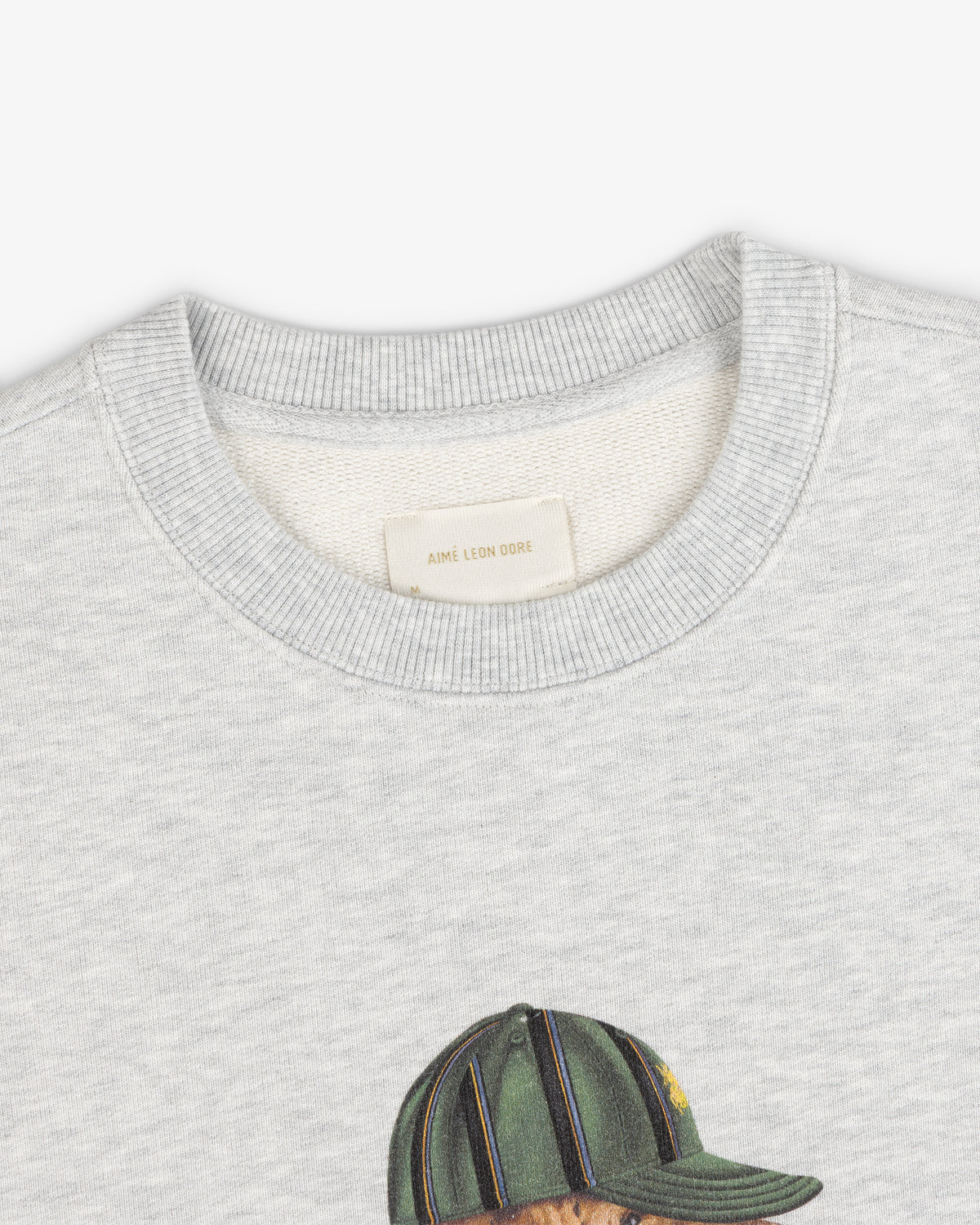 Buddy Crewneck Sweatshirt in light gray with neck tag and top of printed green cap design visible.