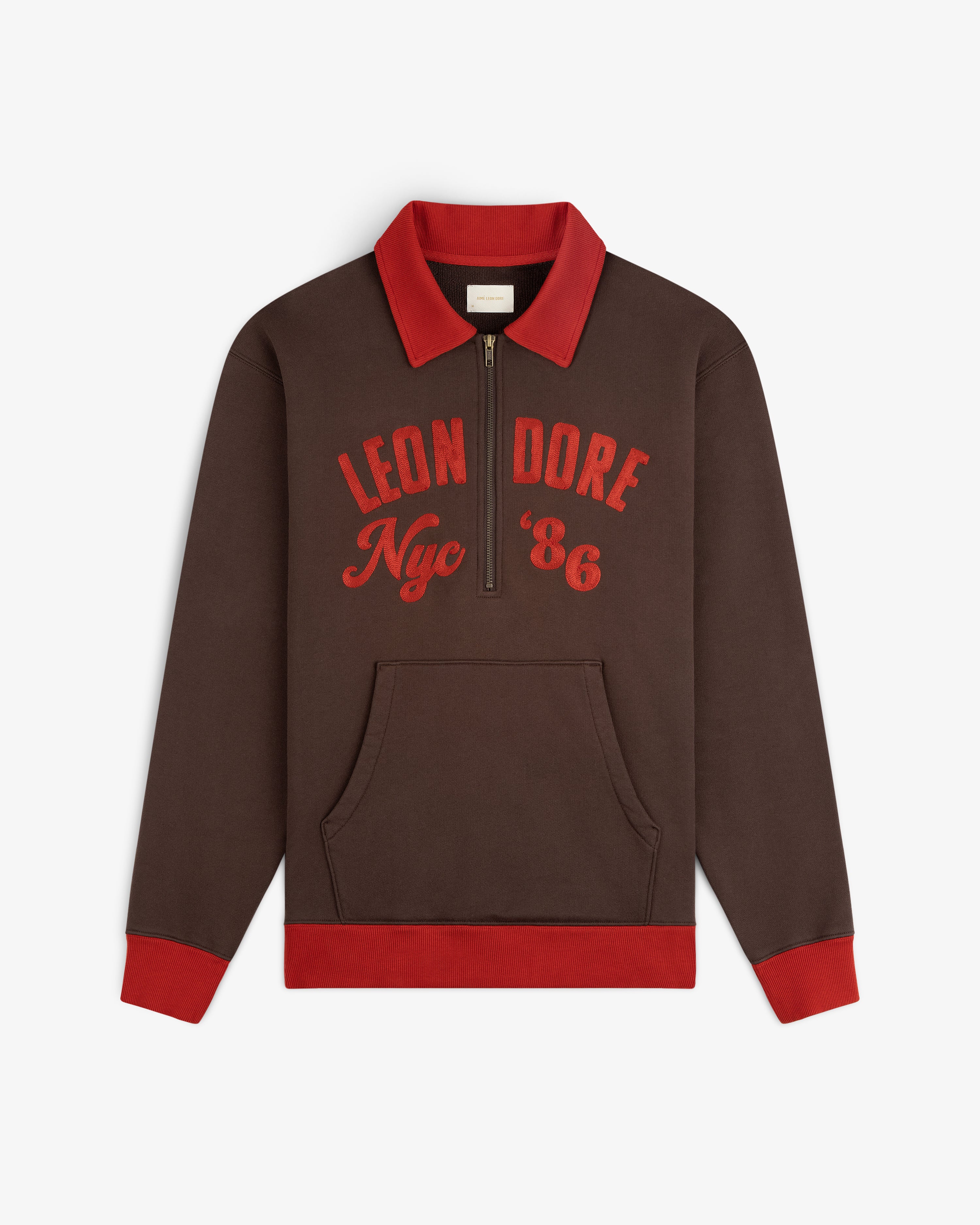 Brown Chainstitch ’86 Half Zip Pullover with red collar, cuffs, and hem, featuring red LEON DORE Nyc 86 embroidery.