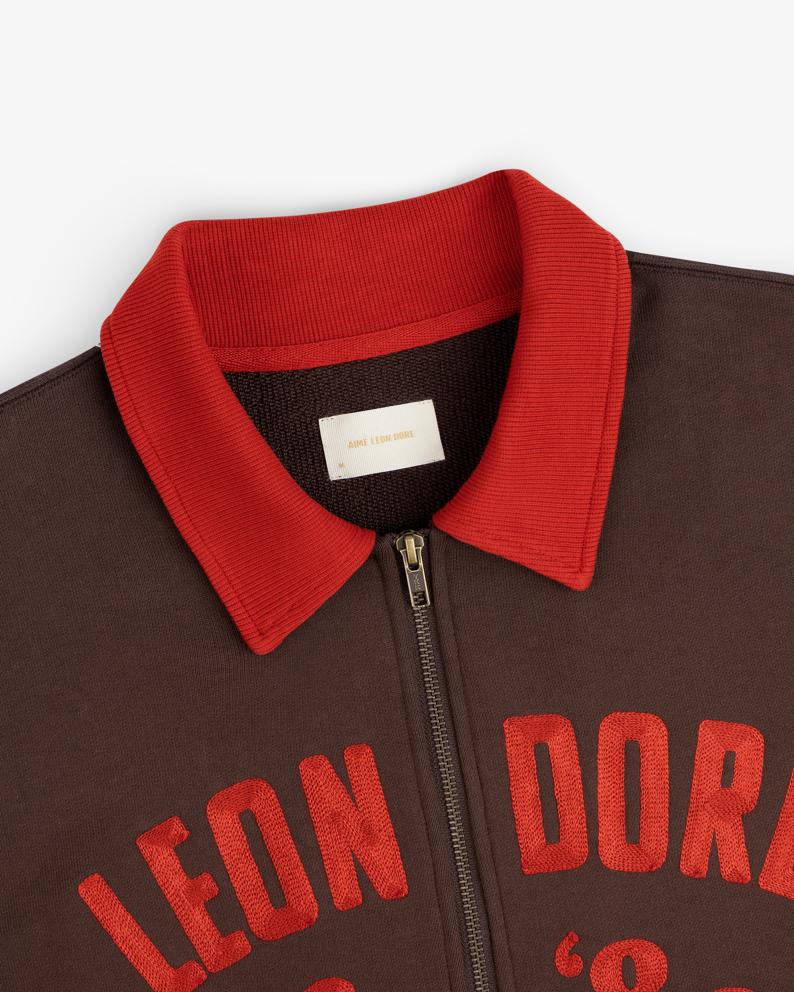 Chainstitch ’86 Half Zip Pullover in brown with a red ribbed collar and red embroidered text across the chest.