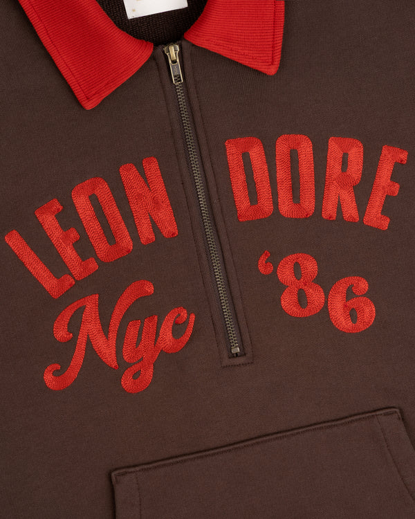 Brown Chainstitch ’86 Half Zip Pullover with a red collar and red embroidered text reading Leon Dore Nyc 86.