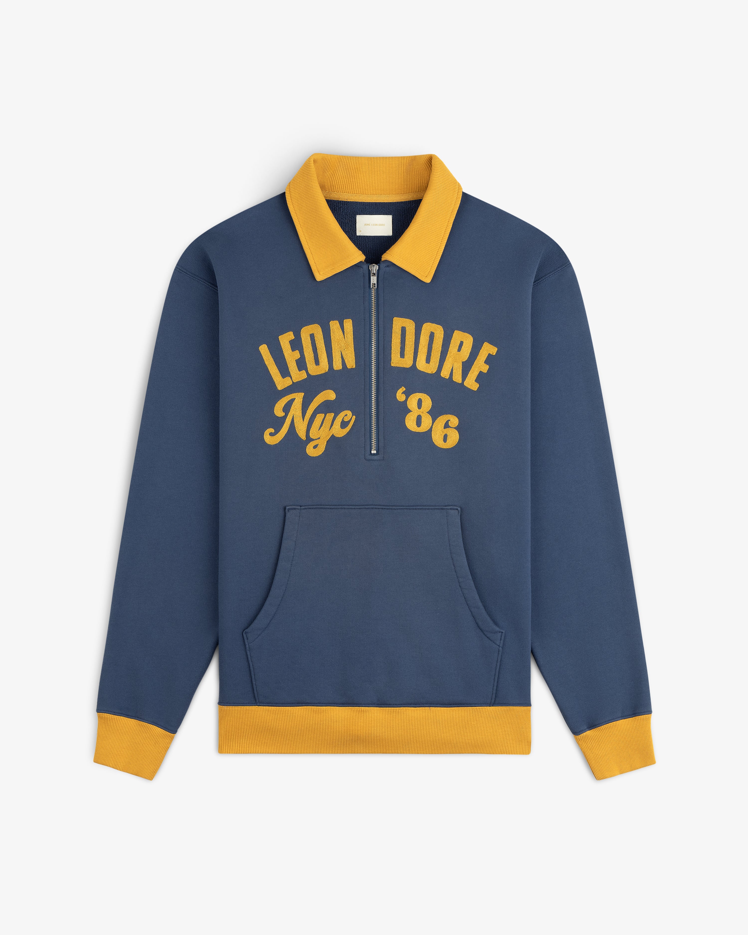 Chainstitch ’86 Half Zip Pullover in navy blue with a yellow collar, cuffs, hem, and gold embroidered chest text.