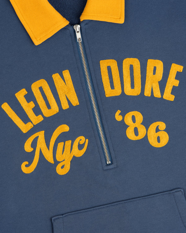 Chainstitch ’86 Half Zip Pullover in blue with a yellow collar and yellow embroidered text reading Leon Dore Nyc 86.