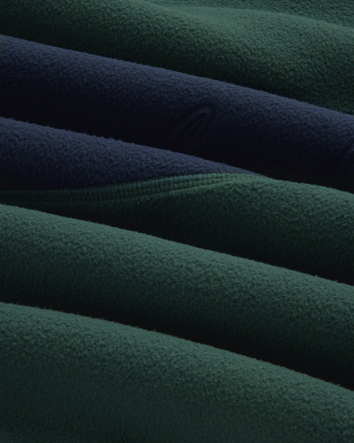 Close-up of a folded dark green and navy blue Fleece Script Paneled Crewneck Sweatshirt.
