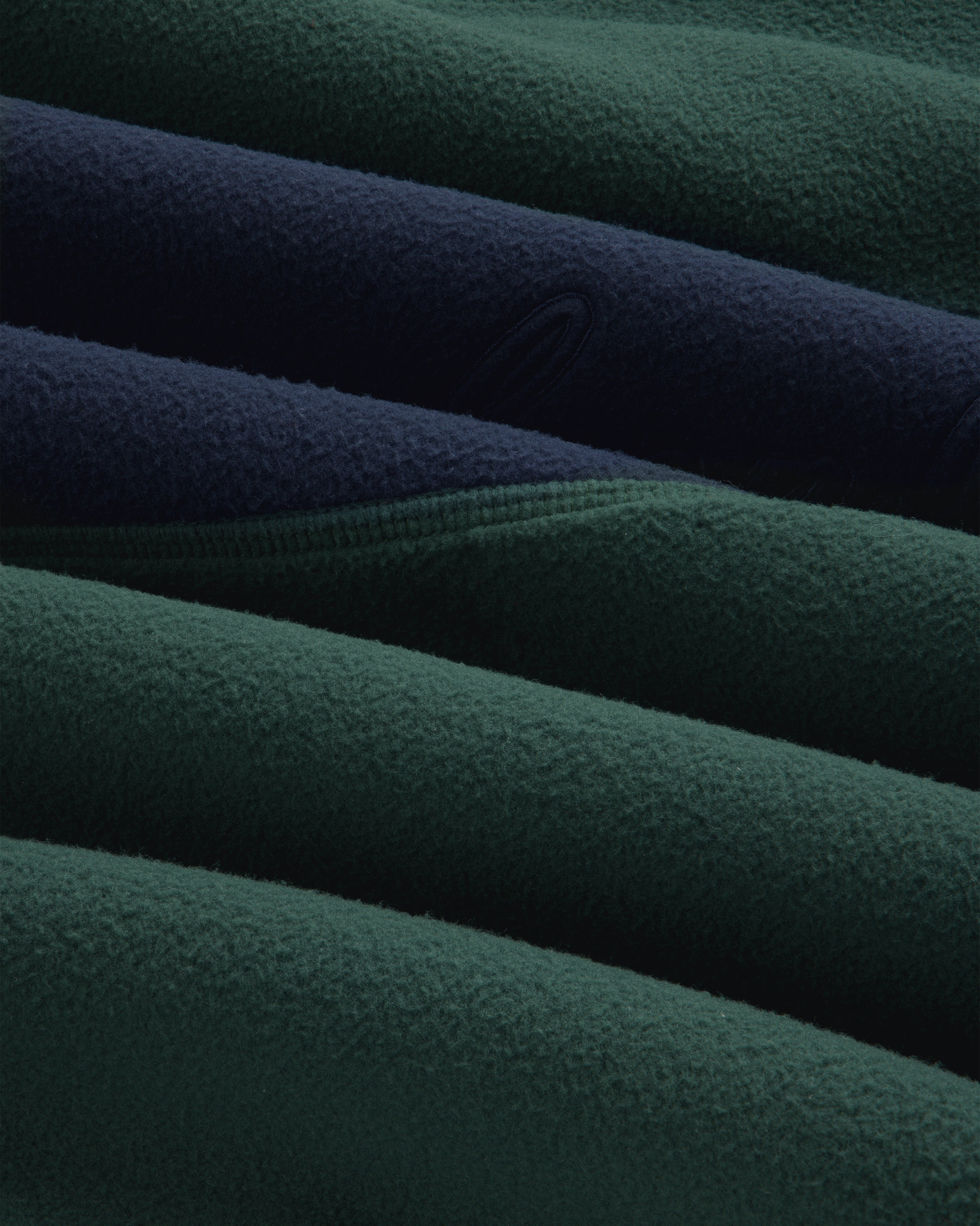 Close-up of a folded dark green and navy blue Fleece Script Paneled Crewneck Sweatshirt.