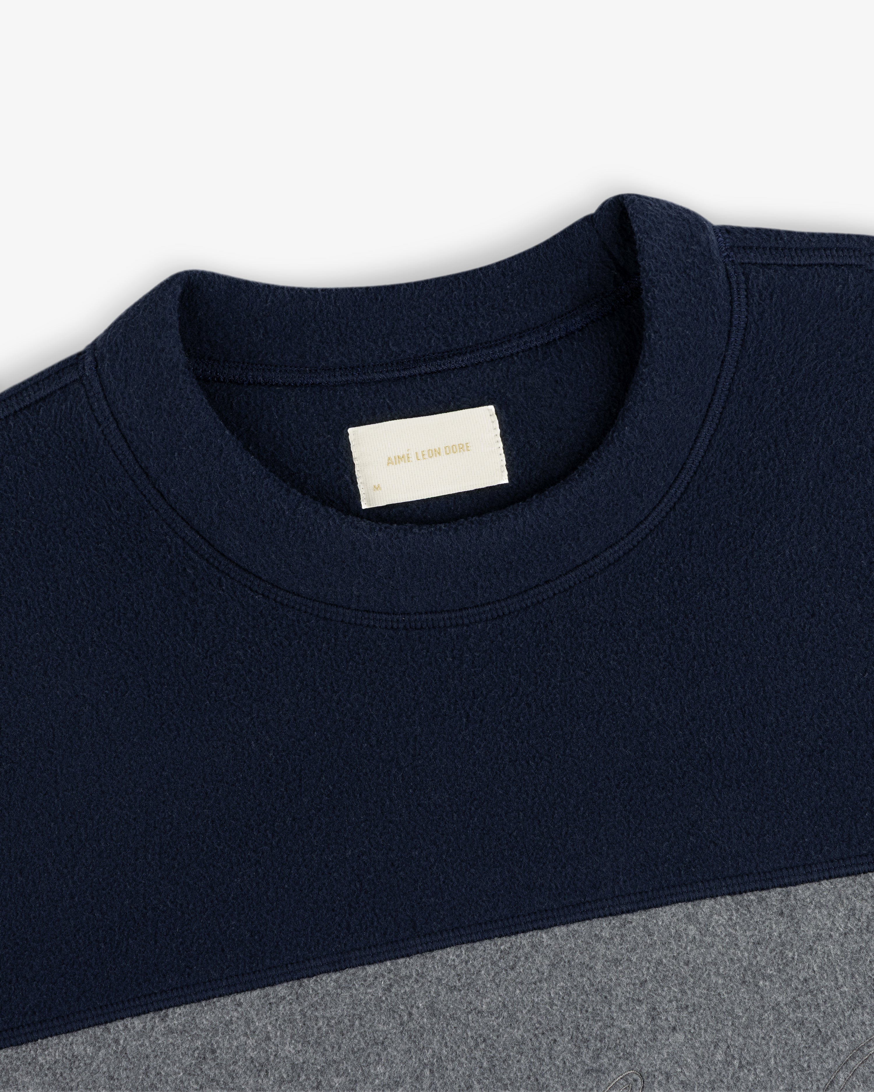 Fleece Script Paneled Crewneck Sweatshirt in navy and gray, color-blocked with a brand label at the collar.