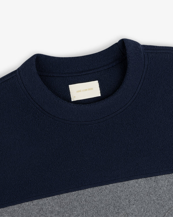 Fleece Script Paneled Crewneck Sweatshirt in navy and gray, color-blocked with a brand label at the collar.