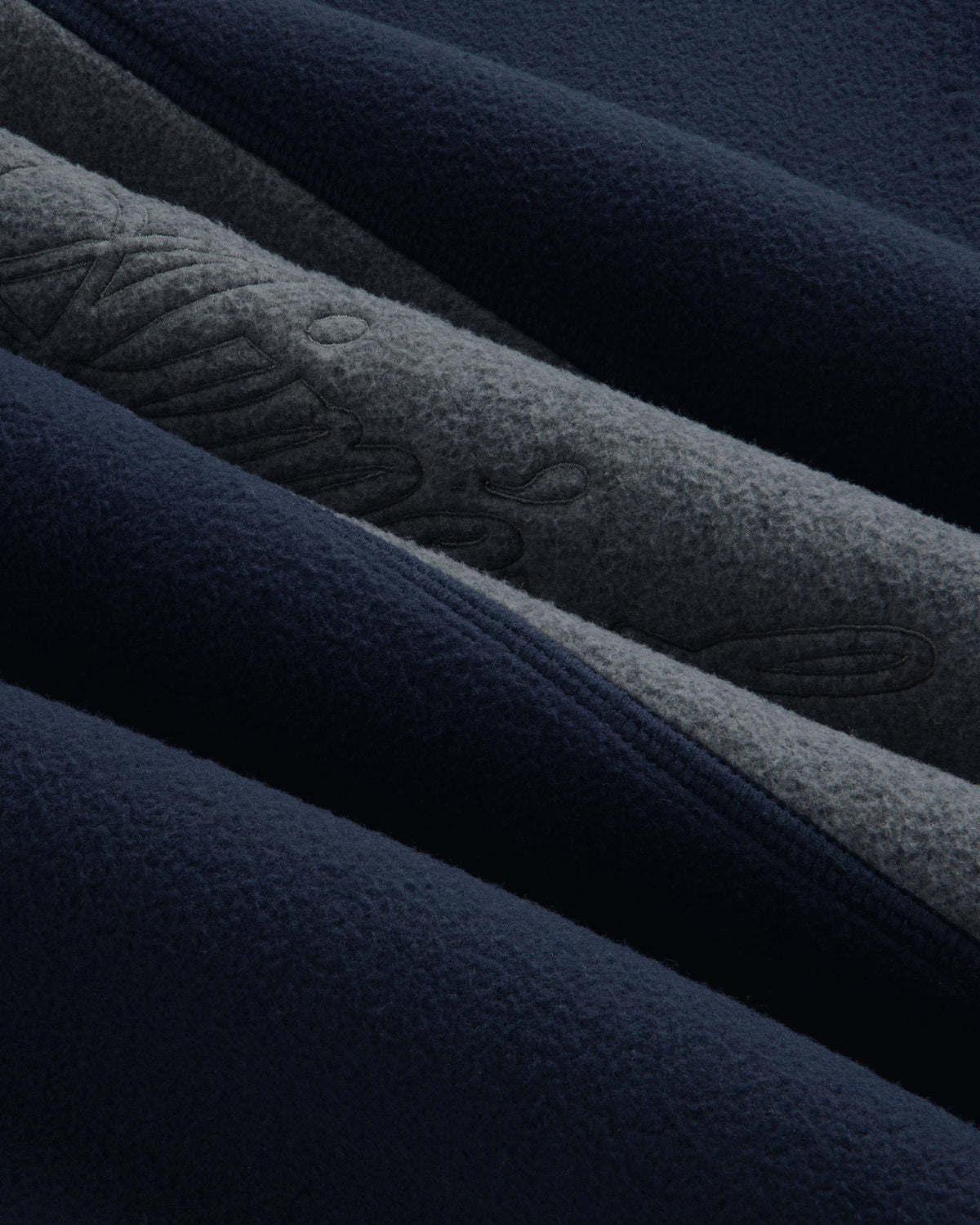 Close-up of a Fleece Script Paneled Crewneck Sweatshirt showing navy and grey fleece panels with embroidered lettering.