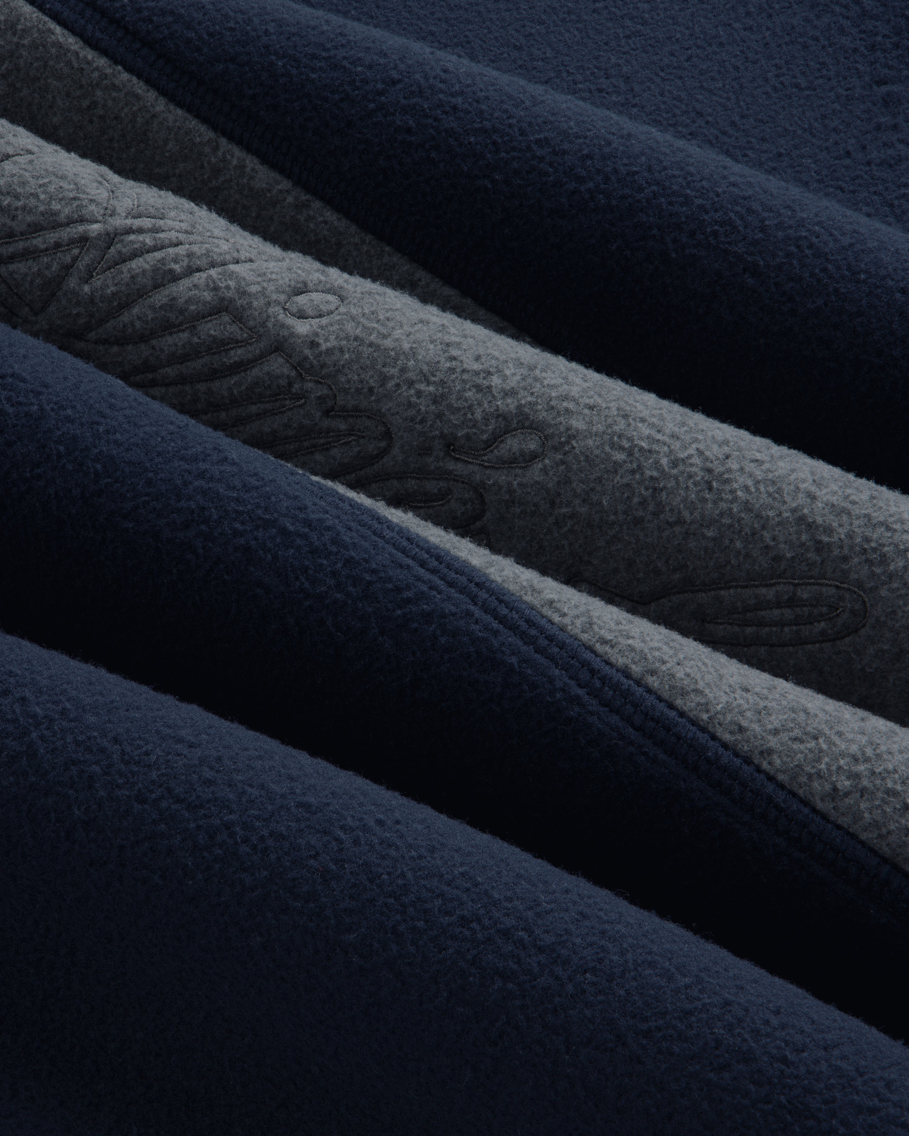 Close-up of a Fleece Script Paneled Crewneck Sweatshirt showing navy and grey fleece panels with embroidered lettering.