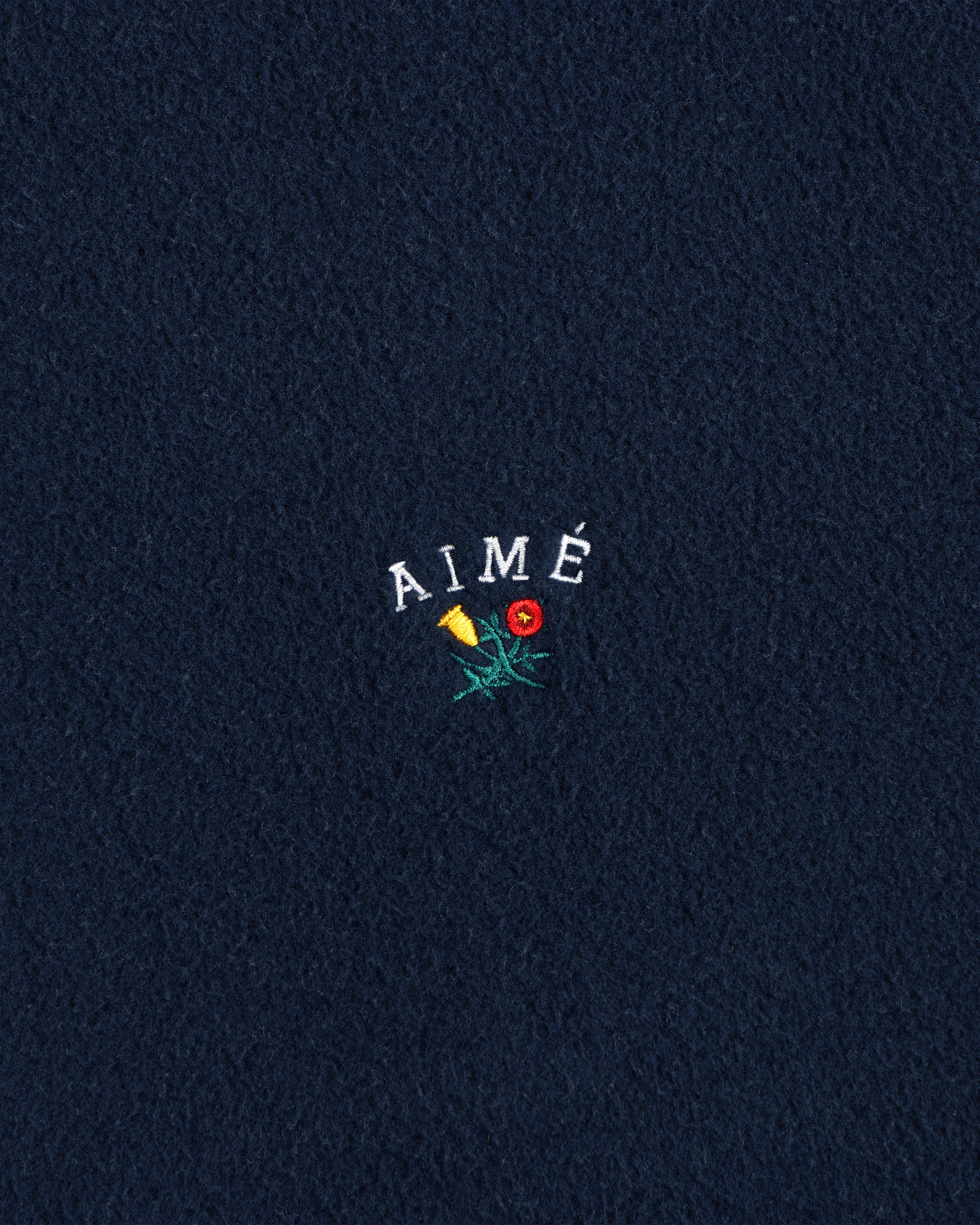 Navy Crest Fleece Casual Jacket with AIMÉ embroidered above a yellow and red flower on the center.