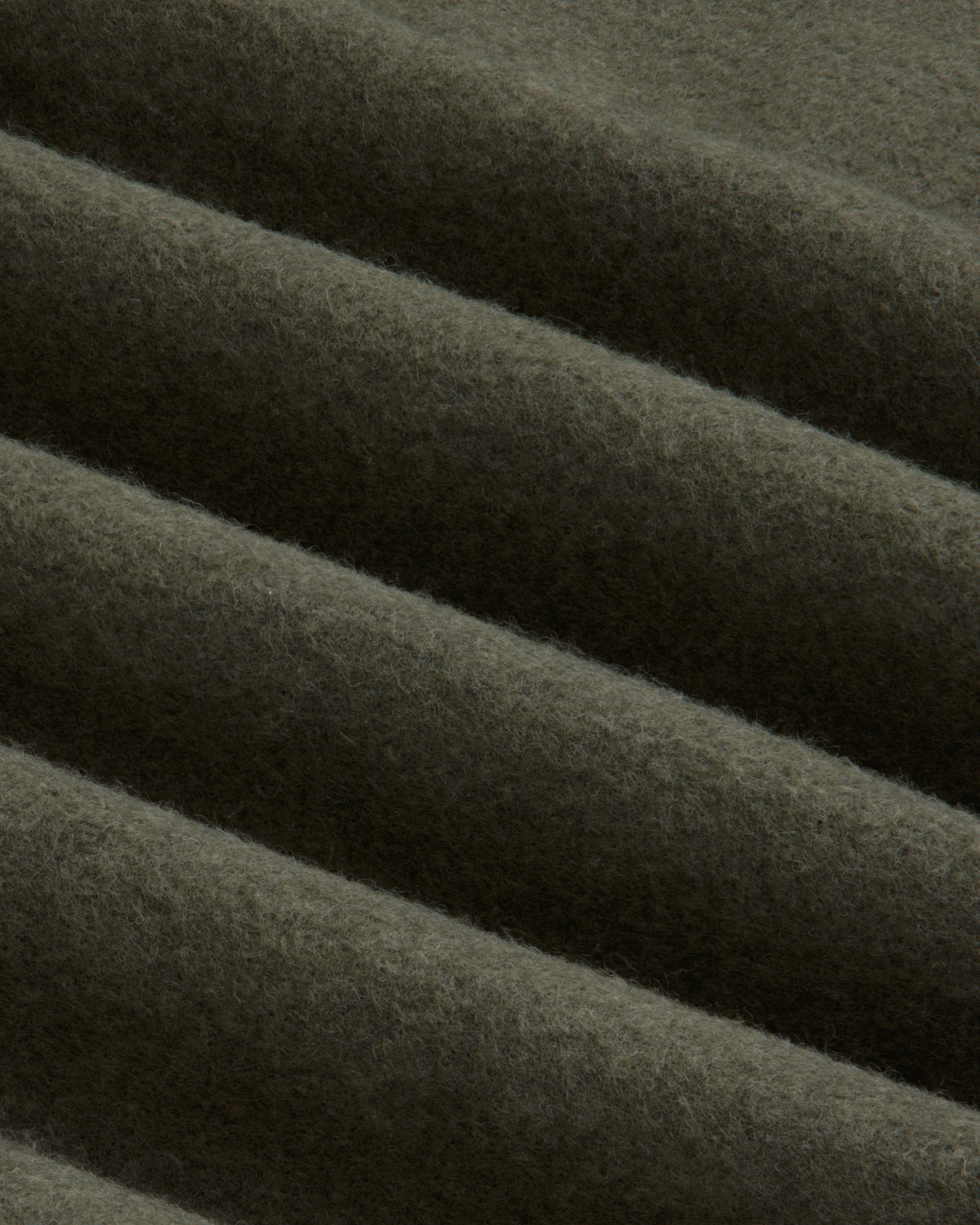 Close-up of olive green Surplus Fleece Quarter Zip Pullover fabric with soft, diagonal folds.