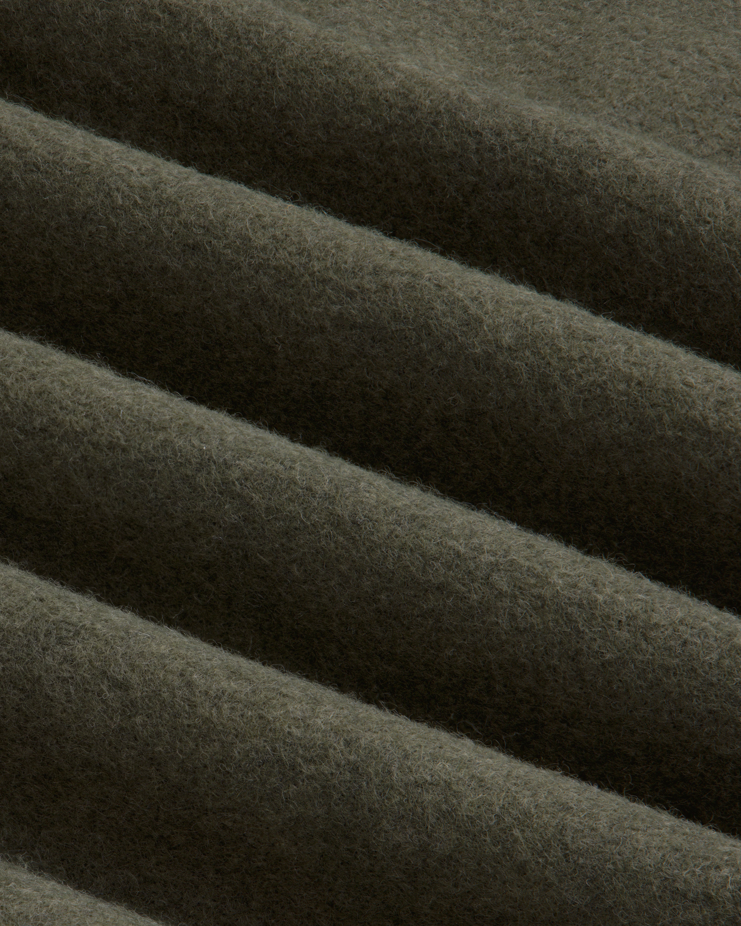 Close-up of olive green Surplus Fleece Quarter Zip Pullover fabric with soft, diagonal folds.