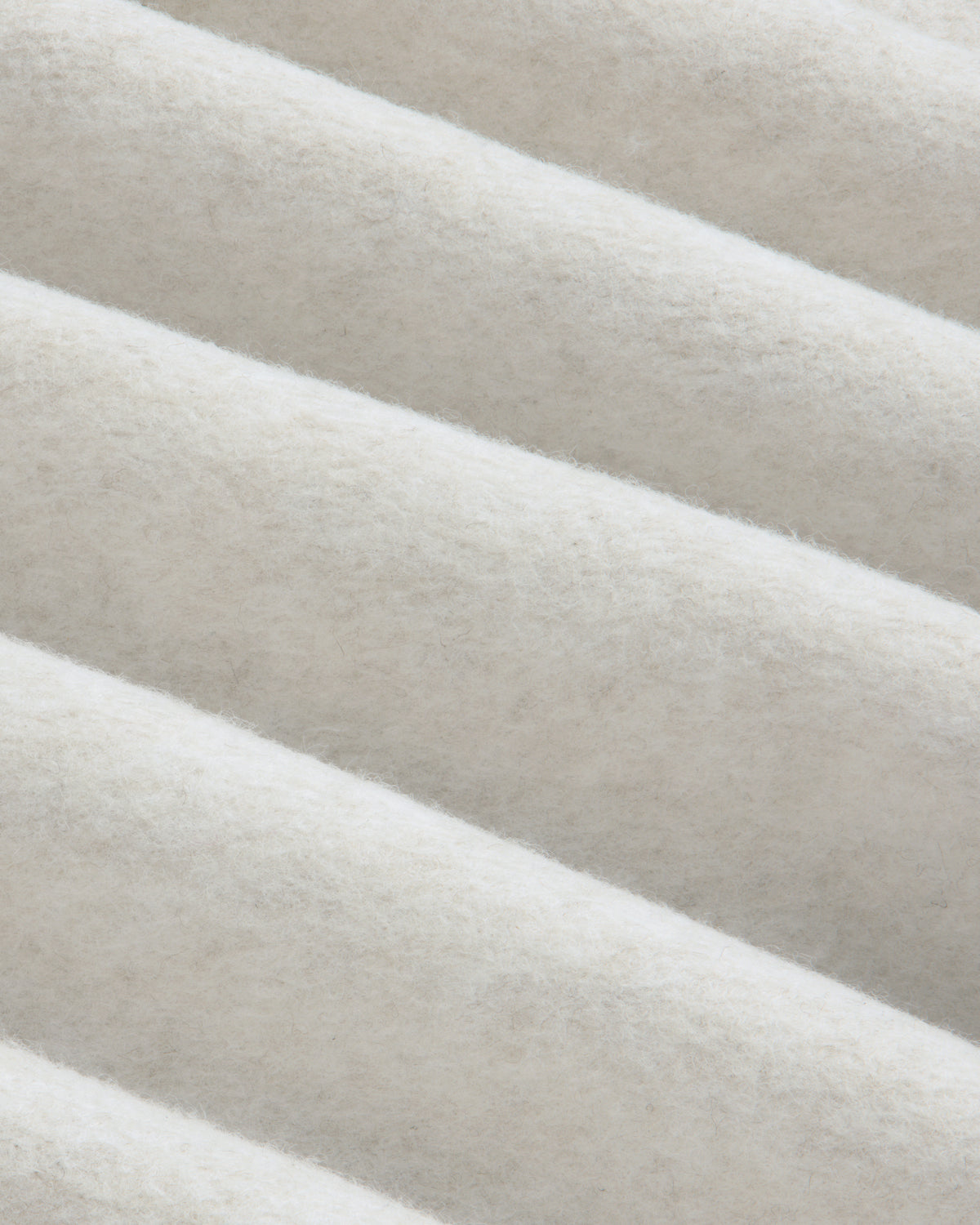 Close-up of beige fleece fabric with diagonal folds on a Surplus Fleece Quarter Zip Pullover.