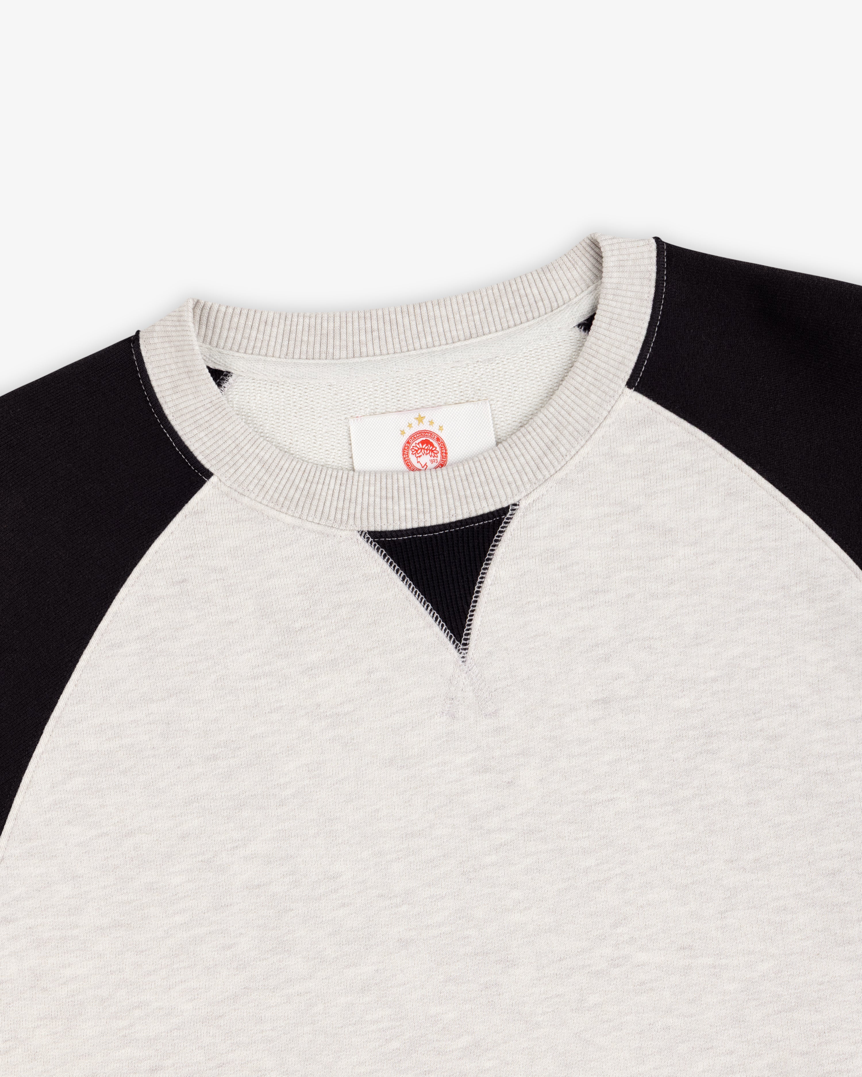 ALD / Olympiacos F.C. Colorblock Crewneck Sweatshirt in off-white with black raglan sleeves and a collar V-insert.