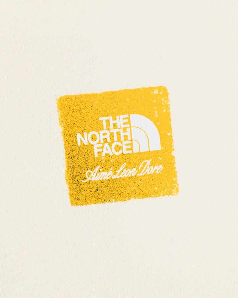 ALD / The North Face Logo Tee with white logos on a rough yellow square, set against a cream background.