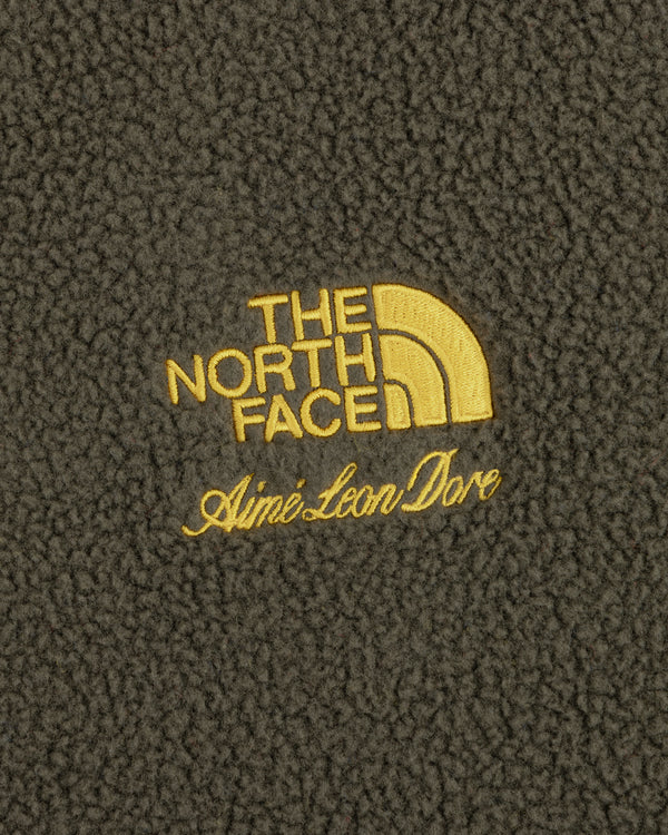 Close-up of yellow ALD / The North Face Fleece Rugby logos on dark fleece fabric.