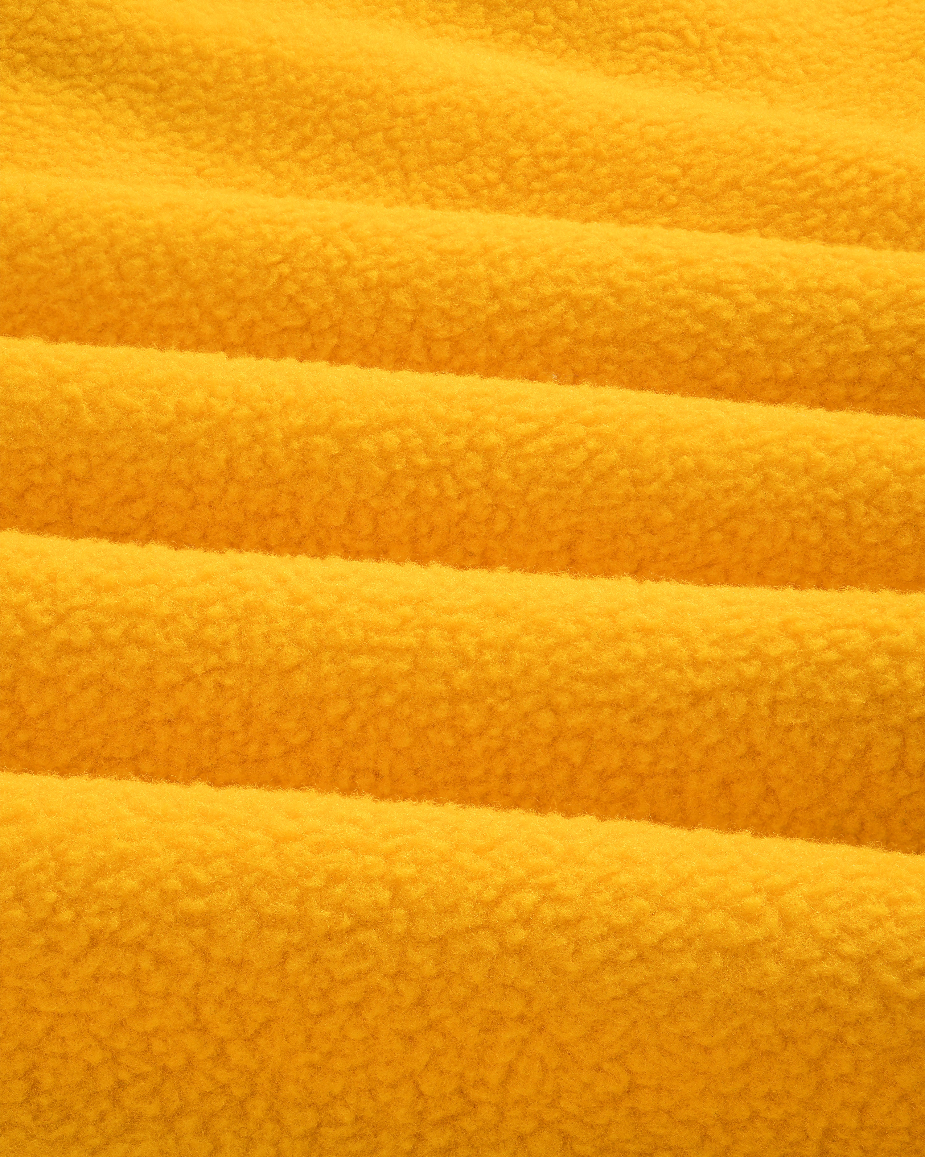 Close-up of soft yellow ALD/The North Face Fleece Rugby, showing textured horizontal folds in the fabric.