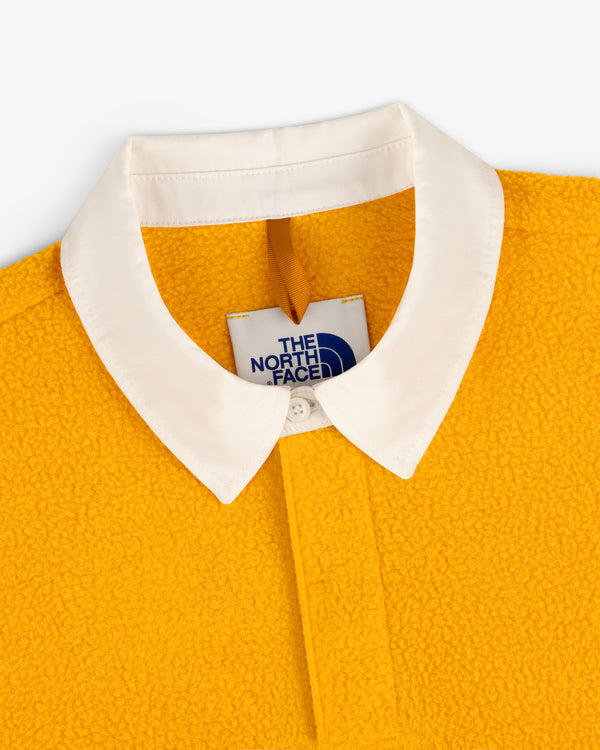 Close-up of ALD / The North Face Fleece Rugby in yellow with a white collar and visible interior label.