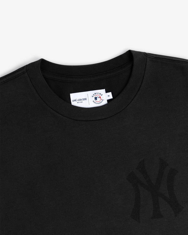 Close-up of a Yankees Washed Logo Tee in black with a subtle logo and neck tag displaying size M.