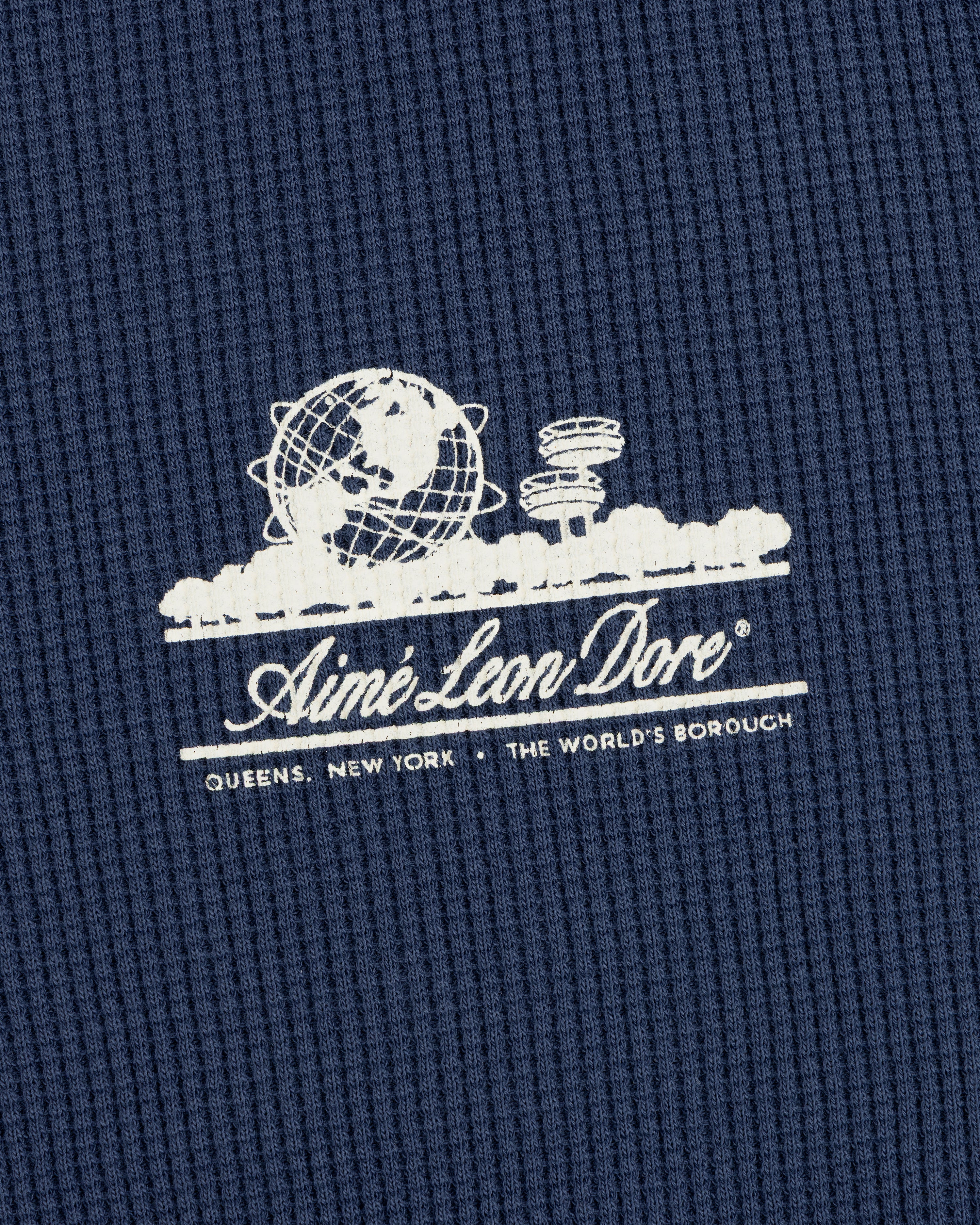 White Aimé Leon Dore Unisphere logo and Queens, NY text on blue Long-Sleeve Unisphere Waffle Thermal.