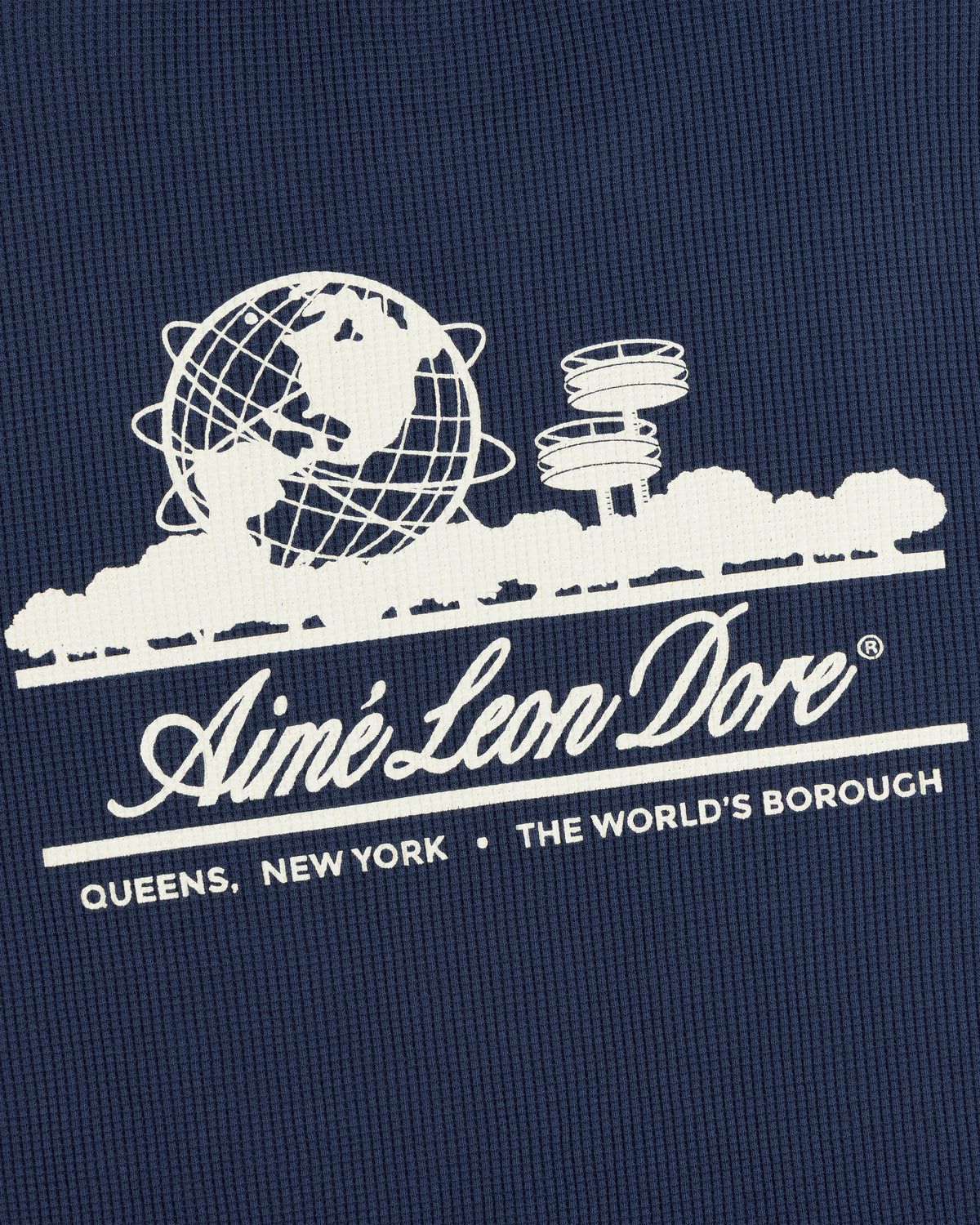 White Aimé Leon Dore globe logo on blue Long-Sleeve Unisphere Waffle Thermal, text reads THE WORLDS BOROUGH.