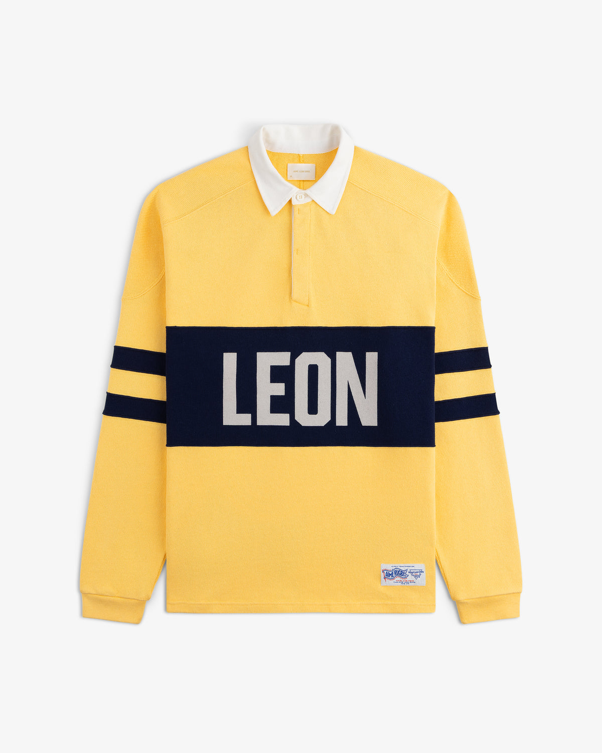 Leon Dore Collegiate Rugby: yellow long-sleeve shirt with white collar, navy stripes, and bold LEON across the chest.