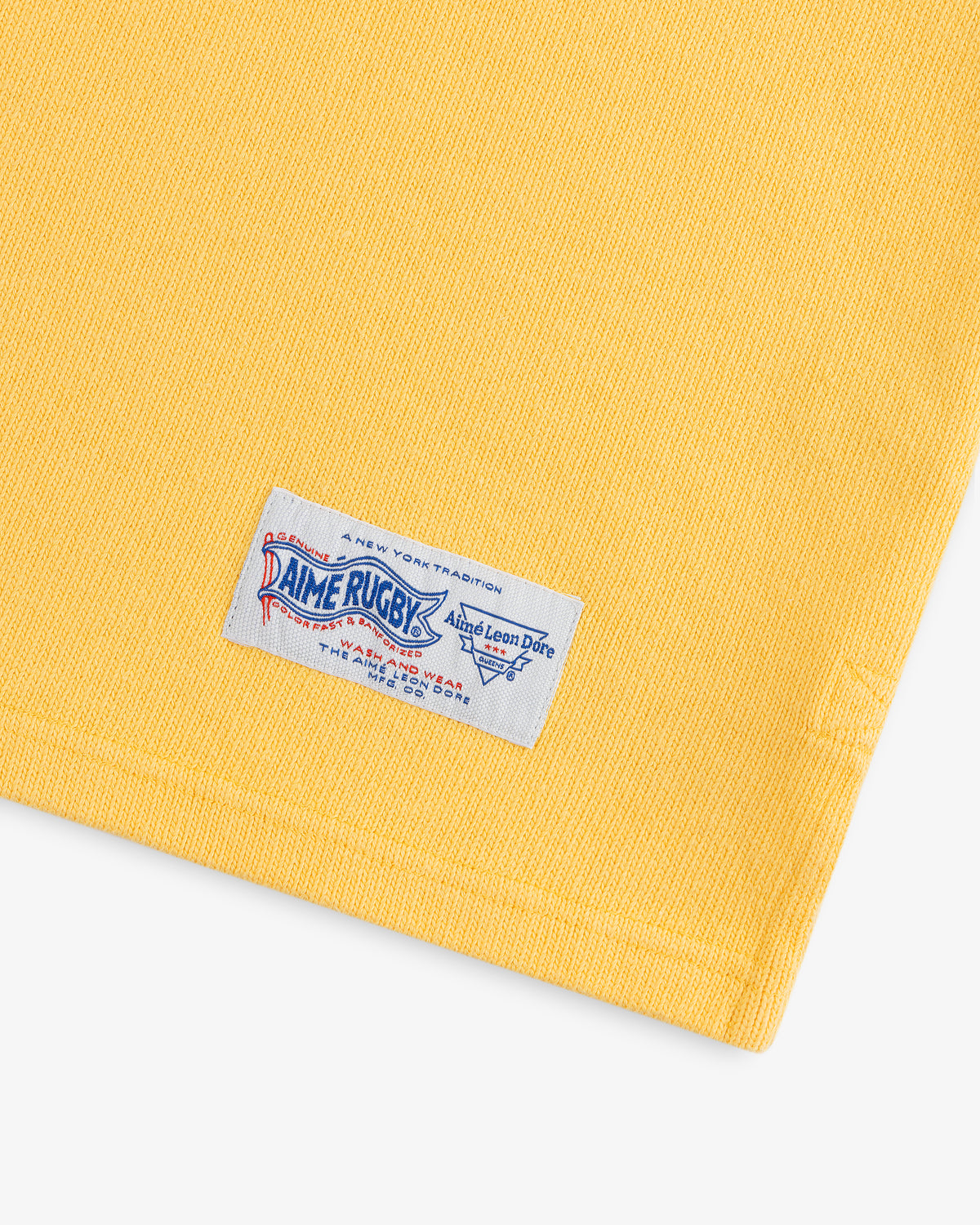Yellow Leon Dore Collegiate Rugby with a white “Rugby” tag near the hem, displayed on a white background.