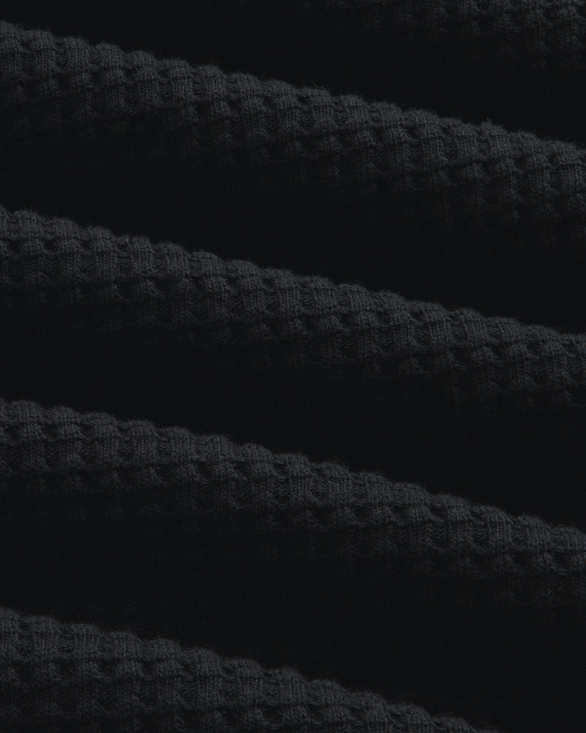 Close-up of black Long-Sleeve Waffle Thermal fabric with a textured waffle-knit pattern.