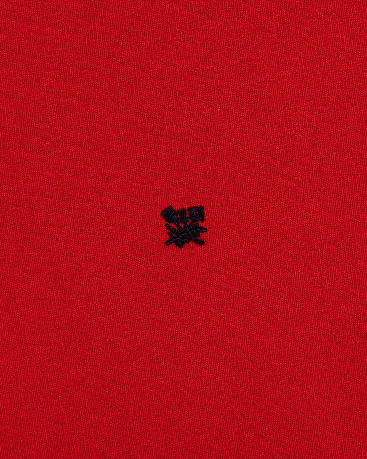 A small black embroidered Crest Rugby logo on bright red textured fabric.
