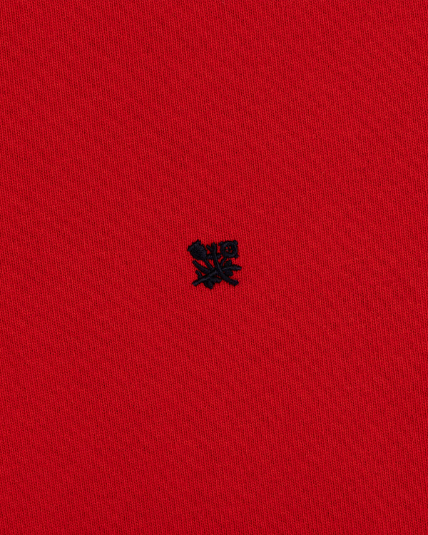 A small black embroidered Crest Rugby logo on bright red textured fabric.