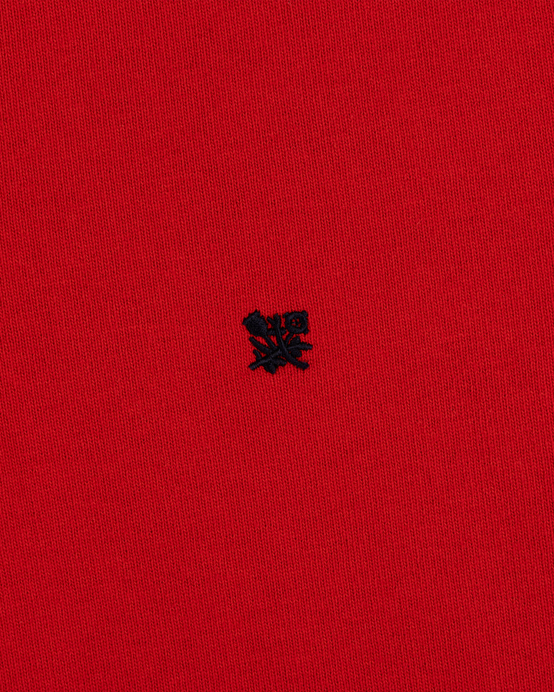 A small black embroidered Crest Rugby logo on bright red textured fabric.