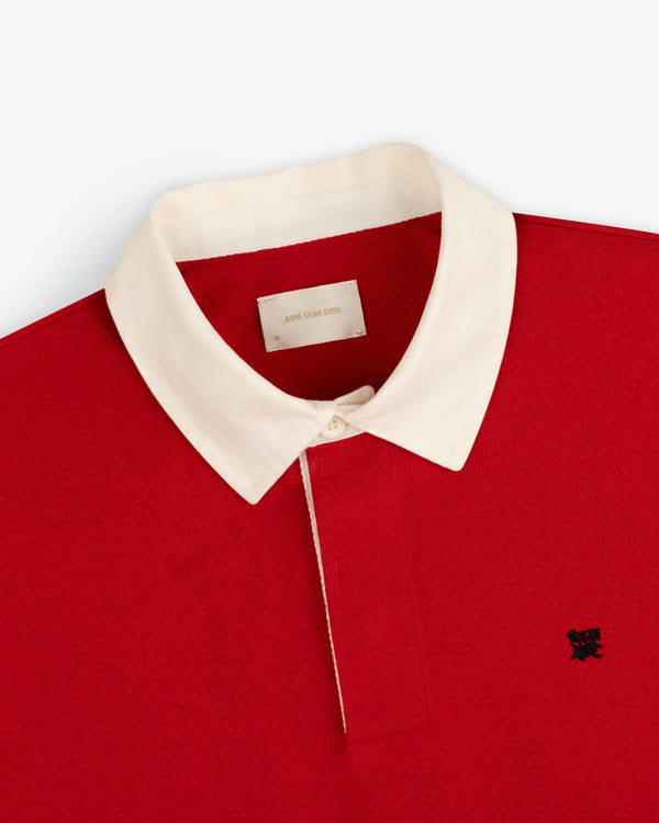 Crest Rugby: Red polo with white collar, white buttons, and small black logo embroidered on chest.