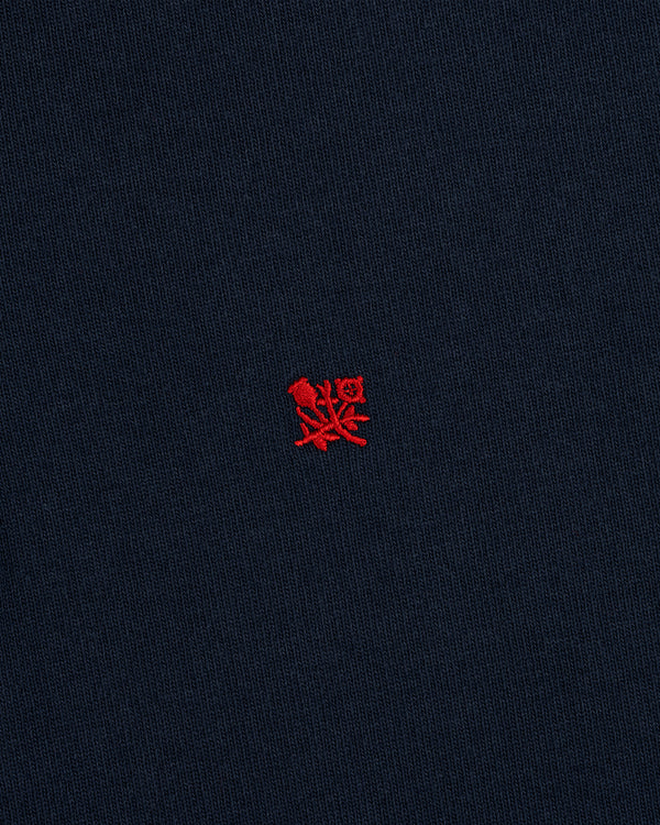 The Crest Rugby features navy blue fabric with a small red embroidered emblem centered on the front.