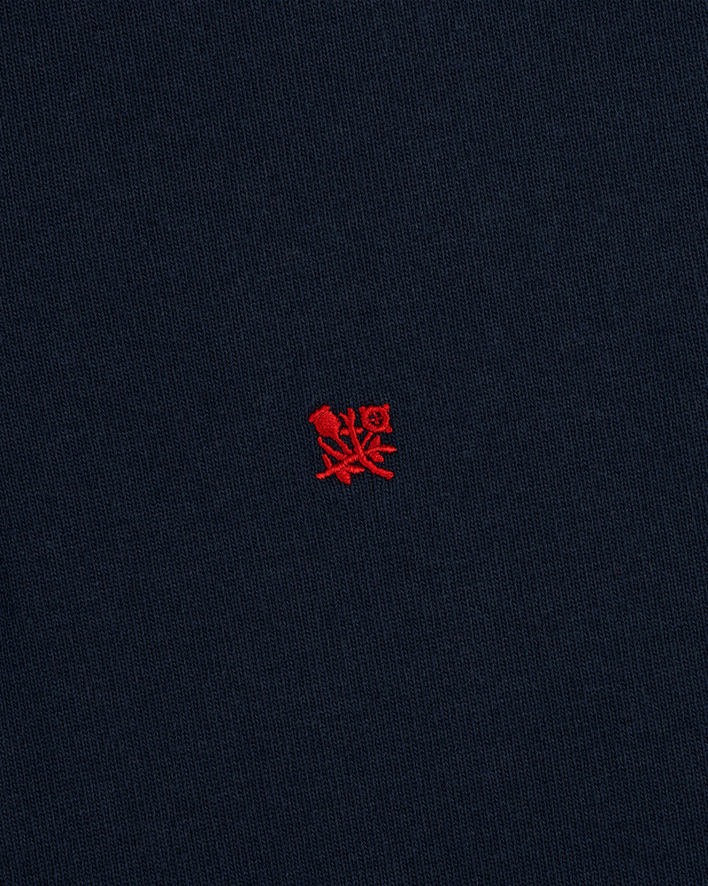 The Crest Rugby features navy blue fabric with a small red embroidered emblem centered on the front.