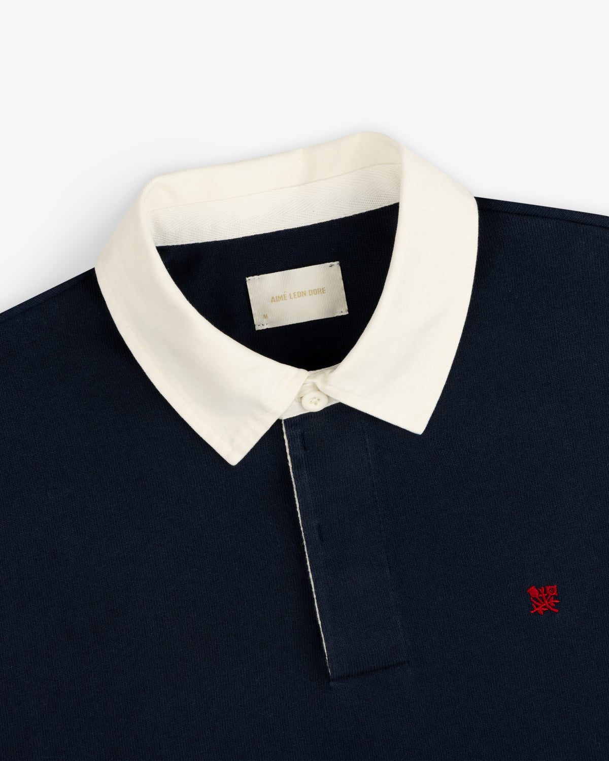 Crest Rugby: Navy polo with white collar, white buttons, and small red chest logo.