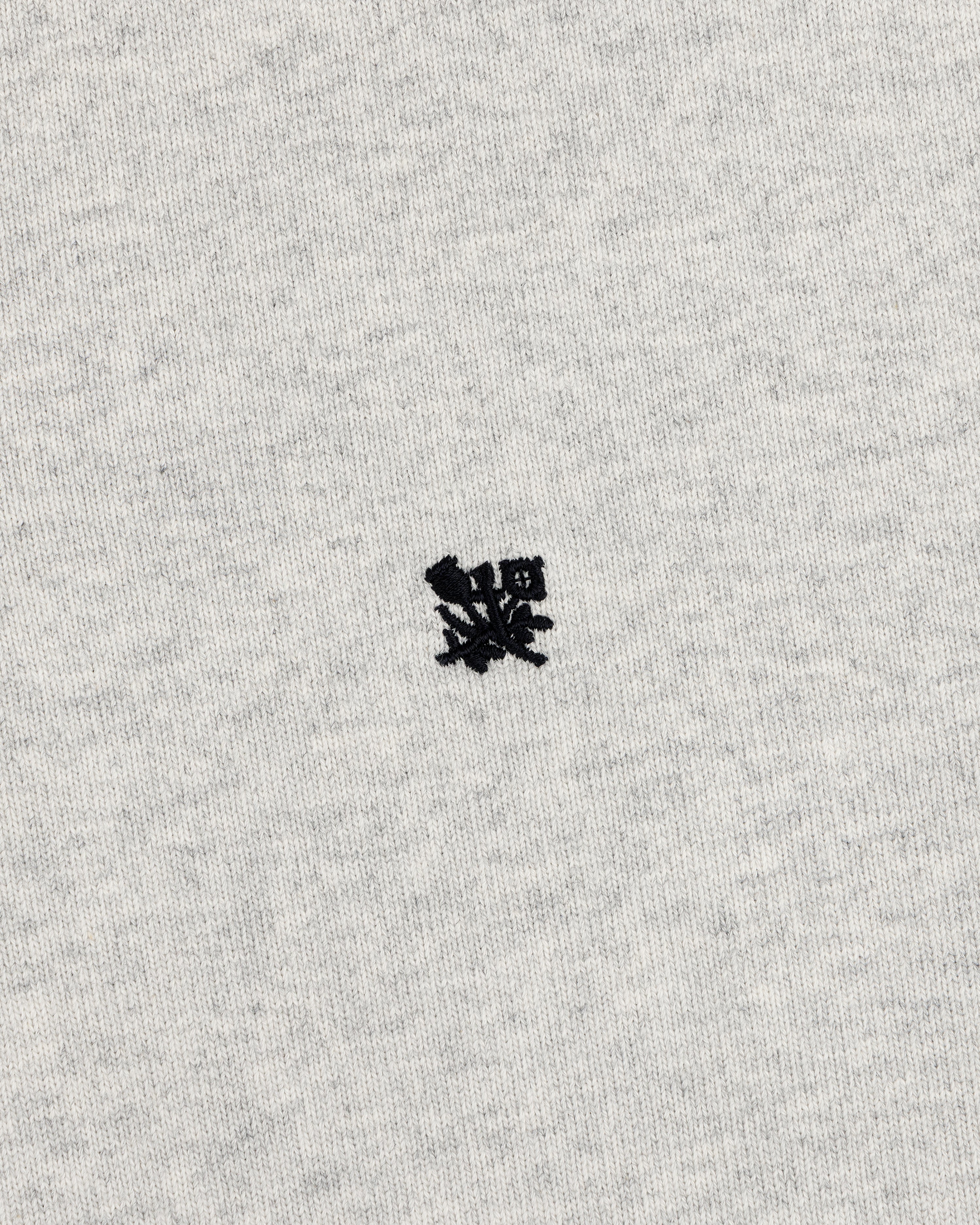 A small black crest is embroidered on the center of the Crest Rugby’s light gray fabric background.