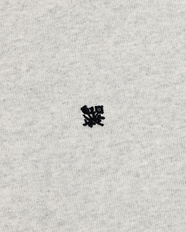 A small black crest is embroidered on the center of the Crest Rugby’s light gray fabric background.