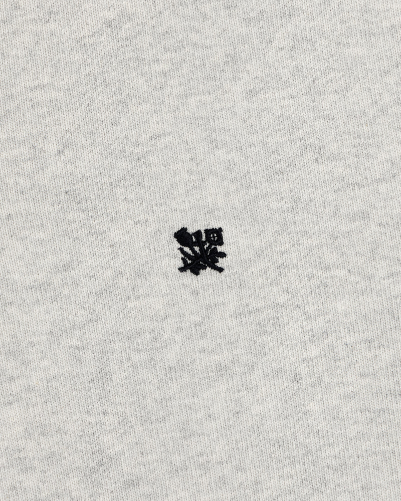 A small black crest is embroidered on the center of the Crest Rugby’s light gray fabric background.