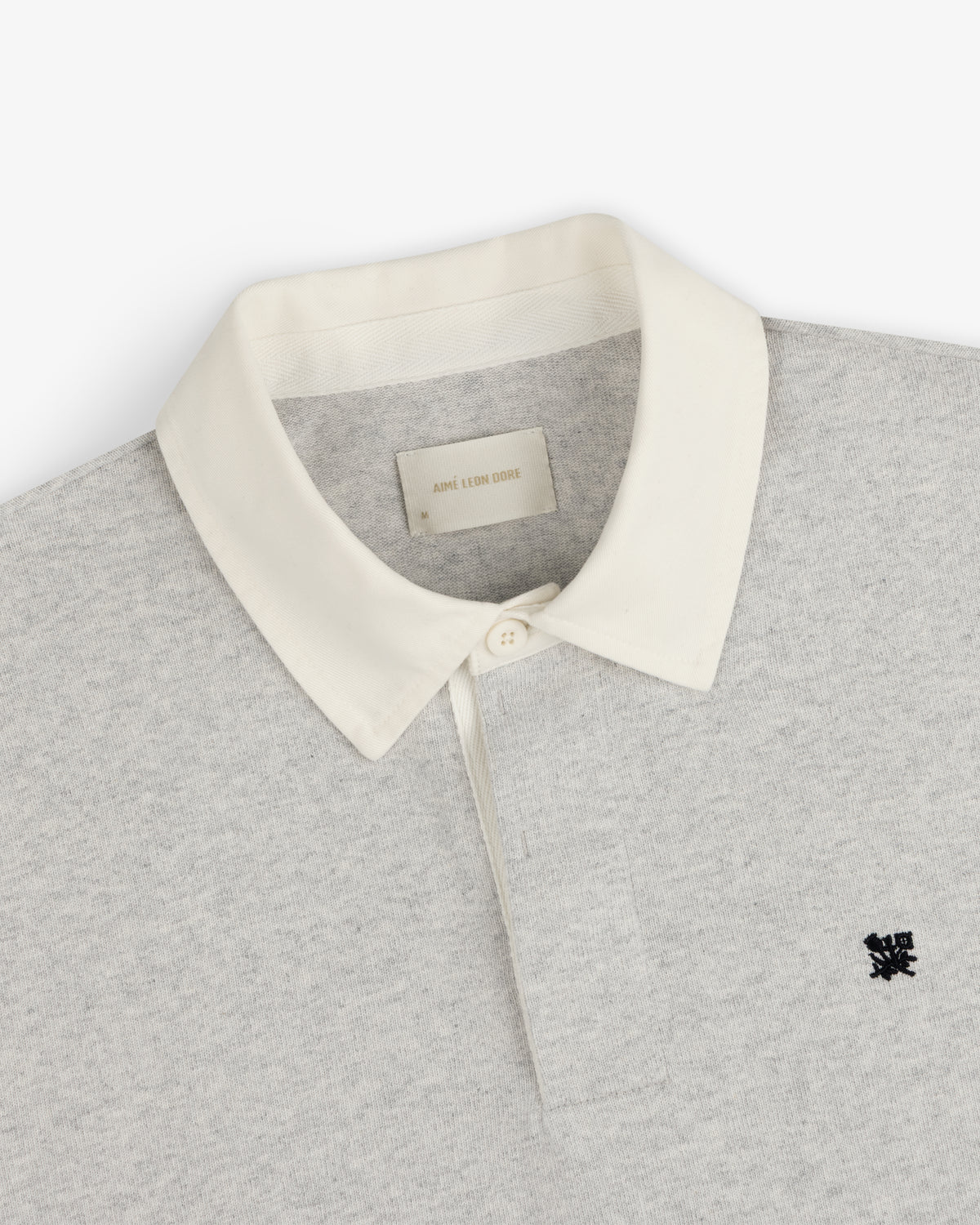 Crest Rugby: Light grey polo with white collar, black chest logo, and inside white neck label.