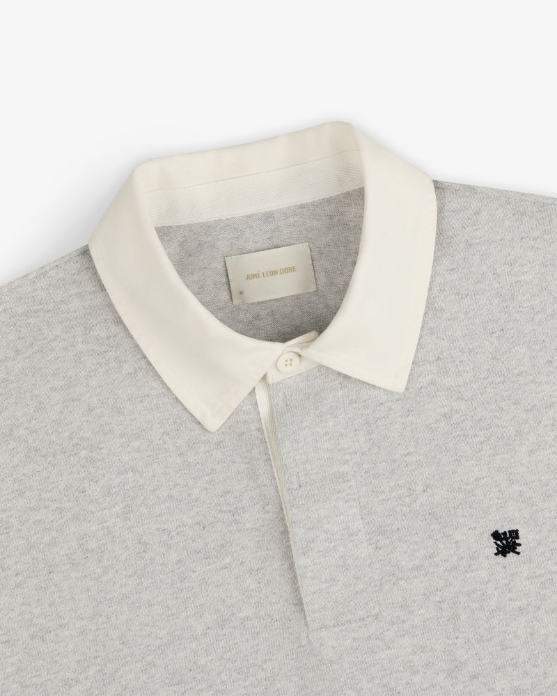 Crest Rugby: Light grey polo with white collar, black chest logo, and inside white neck label.