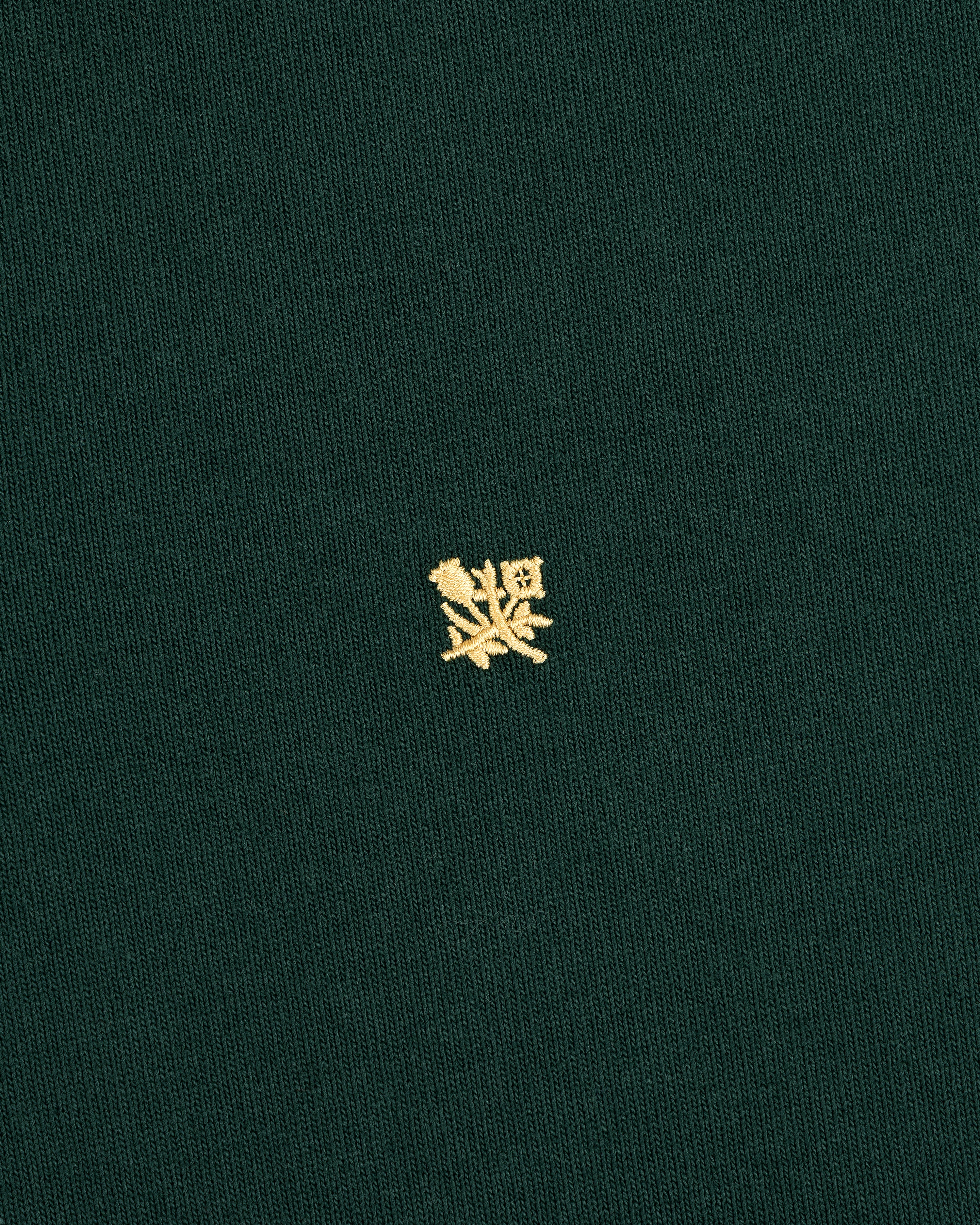 Crest Rugby: Green fabric with a small yellow embroidered crest design centered on the front.