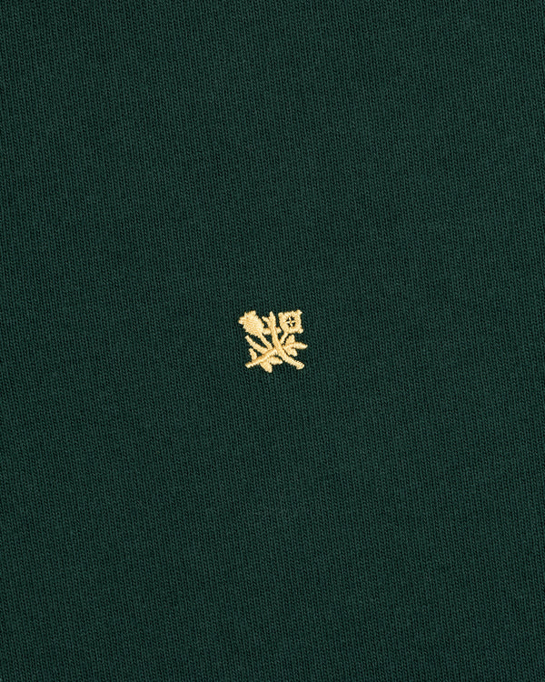 Crest Rugby: Green fabric with a small yellow embroidered crest design centered on the front.
