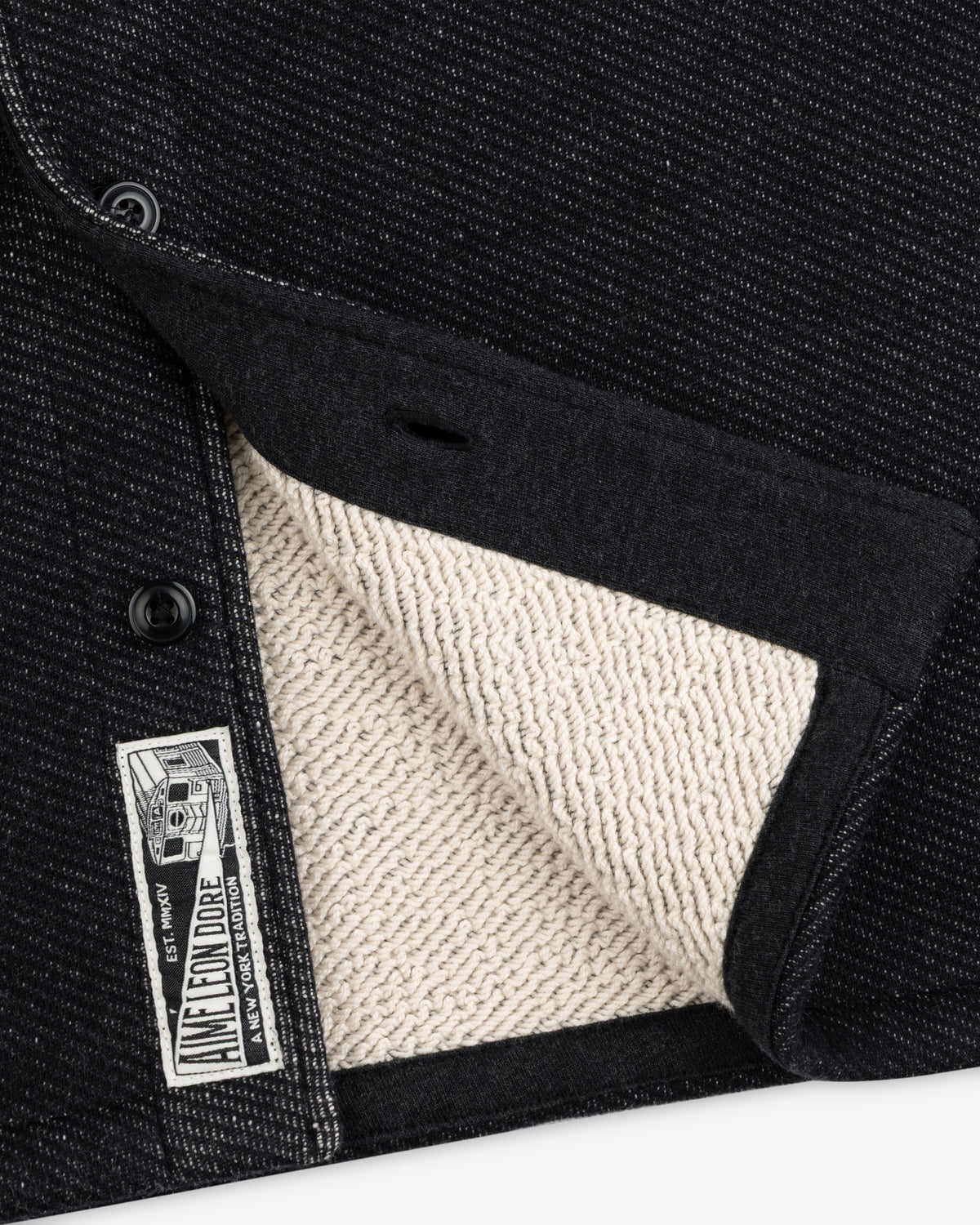 Close-up of a black textured Terry Lounge Shirt with a beige looped interior and a branded label.