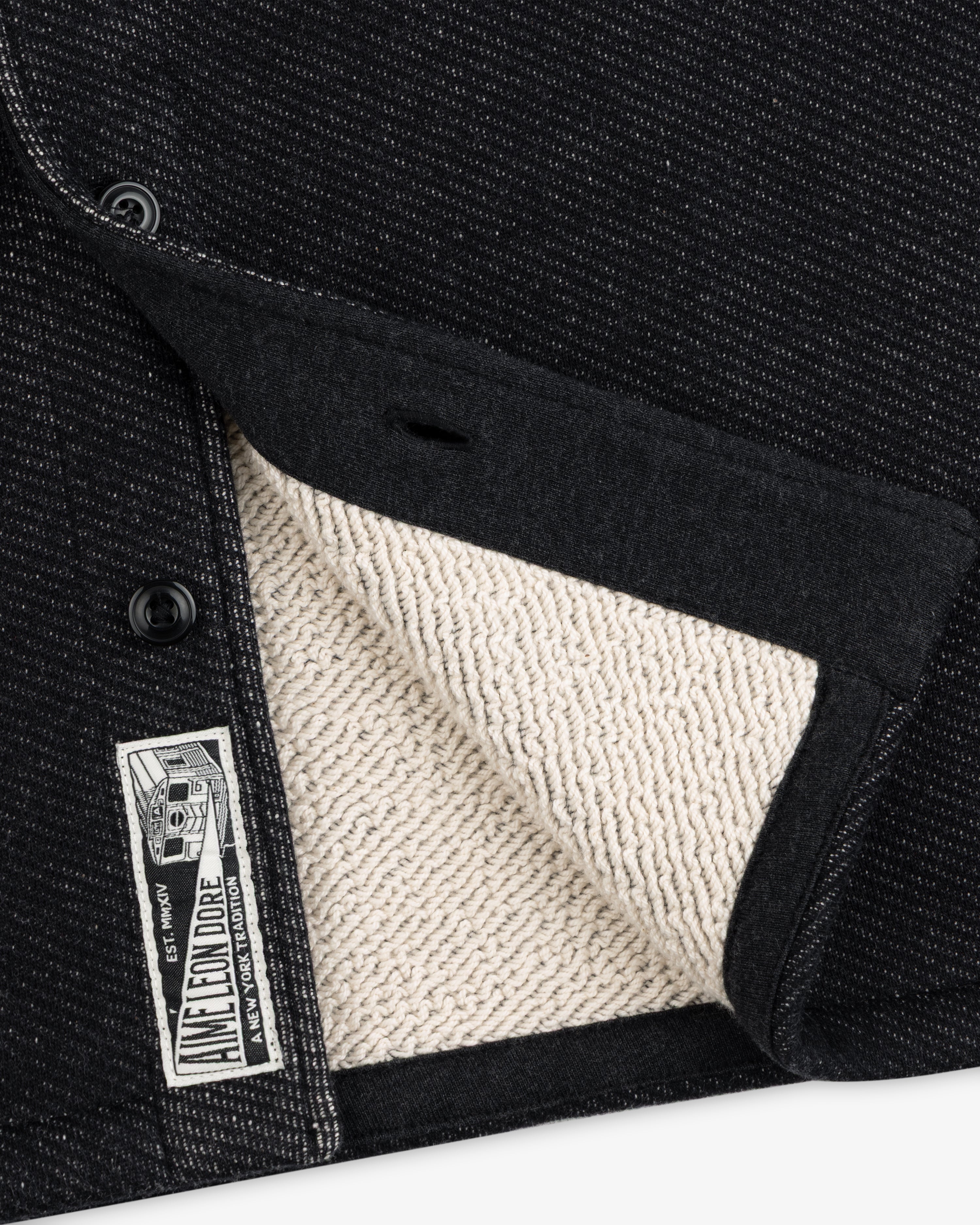 Close-up of a black textured Terry Lounge Shirt with a beige looped interior and a branded label.