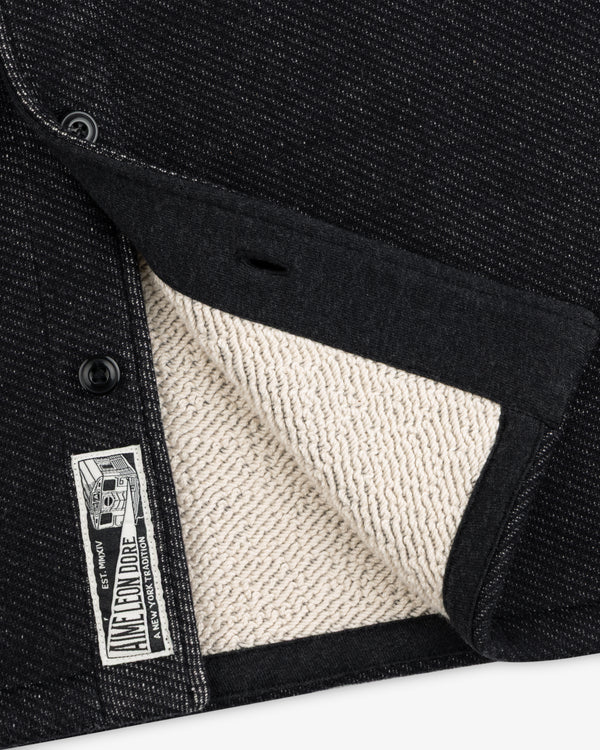 Close-up of a black textured Terry Lounge Shirt with a beige looped interior and a branded label.