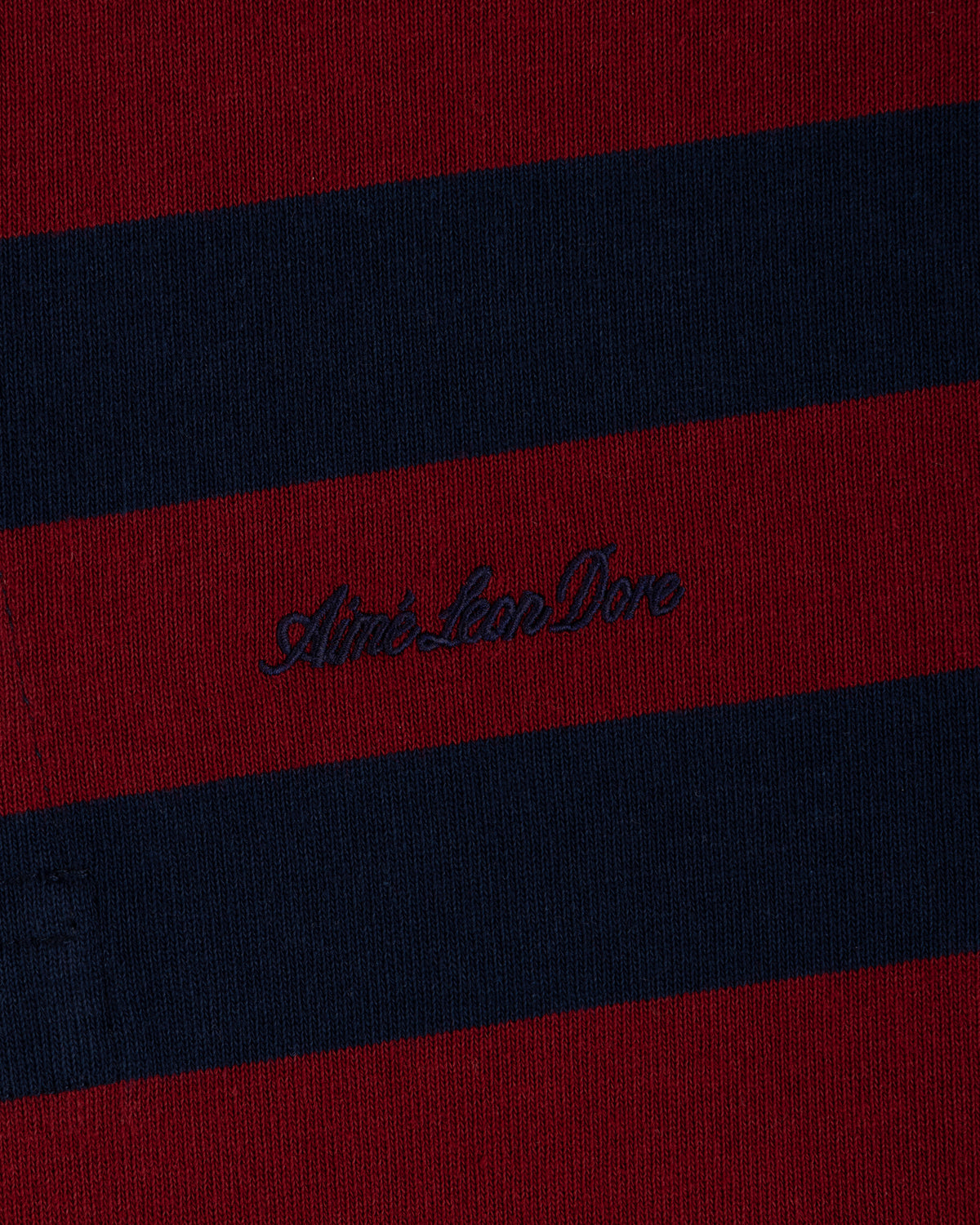 Striped Script Rugby in dark red and navy blue knit fabric with embroidered cursive text in the center.