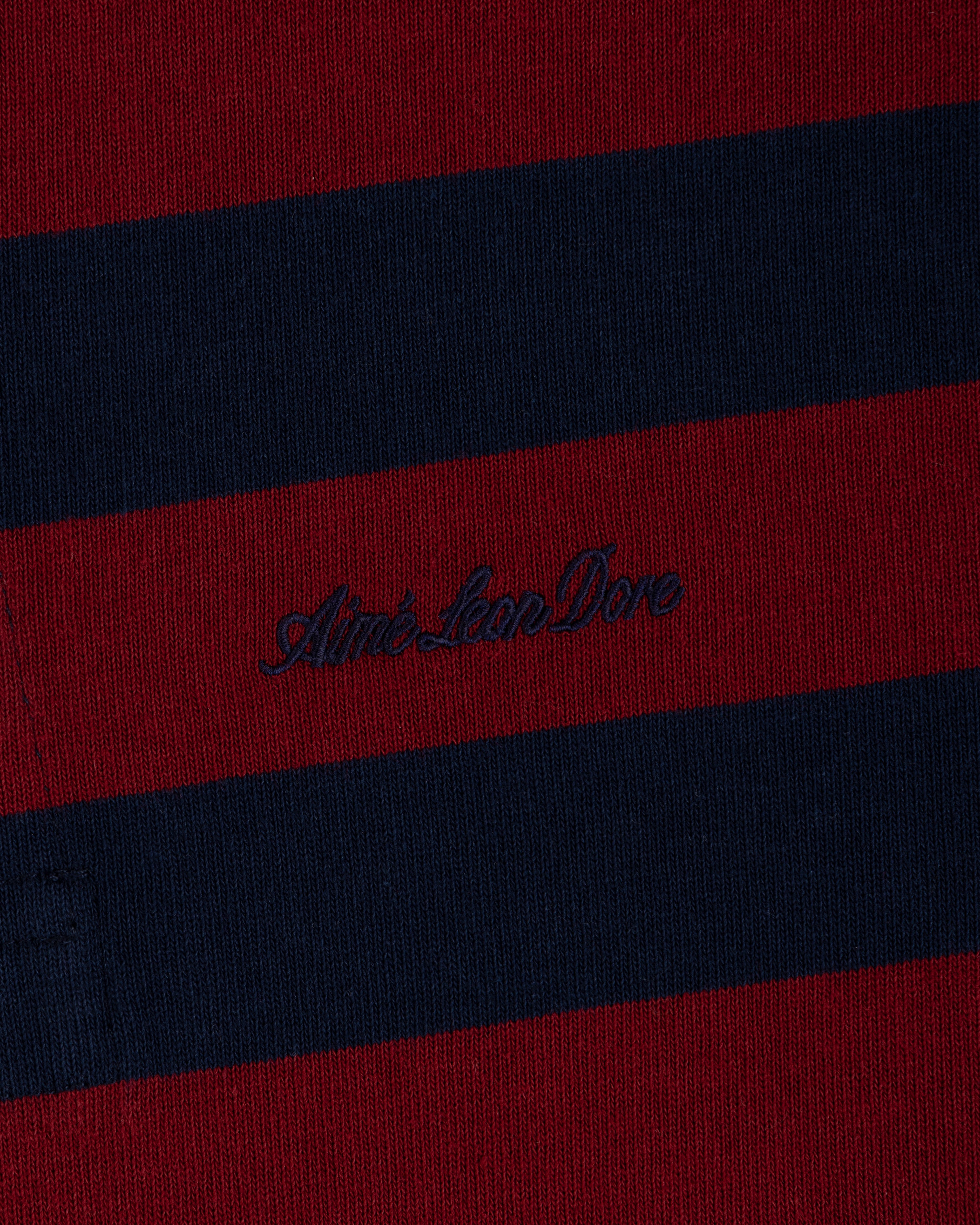 Striped Script Rugby in dark red and navy blue knit fabric with embroidered cursive text in the center.