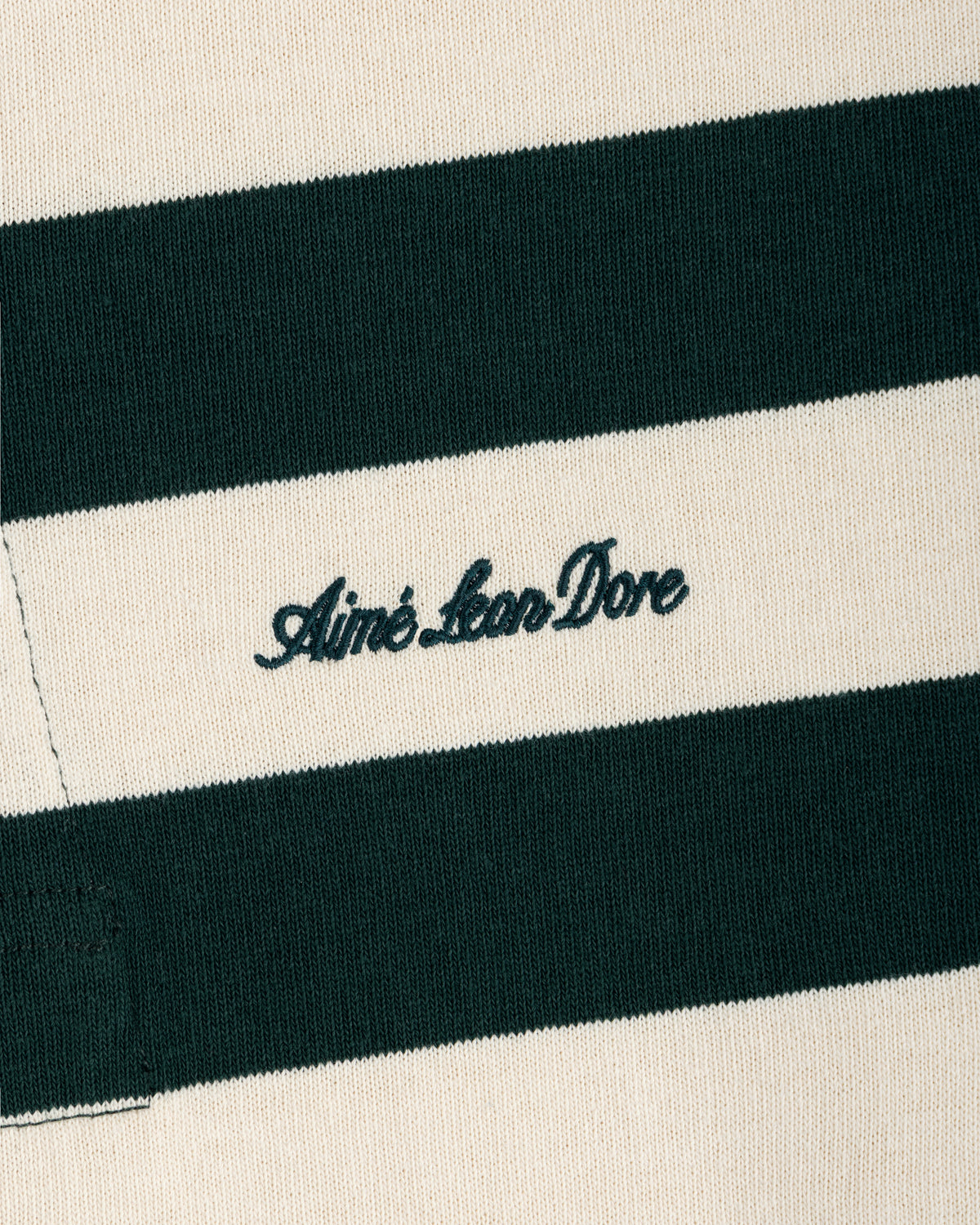 Striped Script Rugby in cream and dark green striped fabric with Aimé Leon Dore embroidered in dark green script.